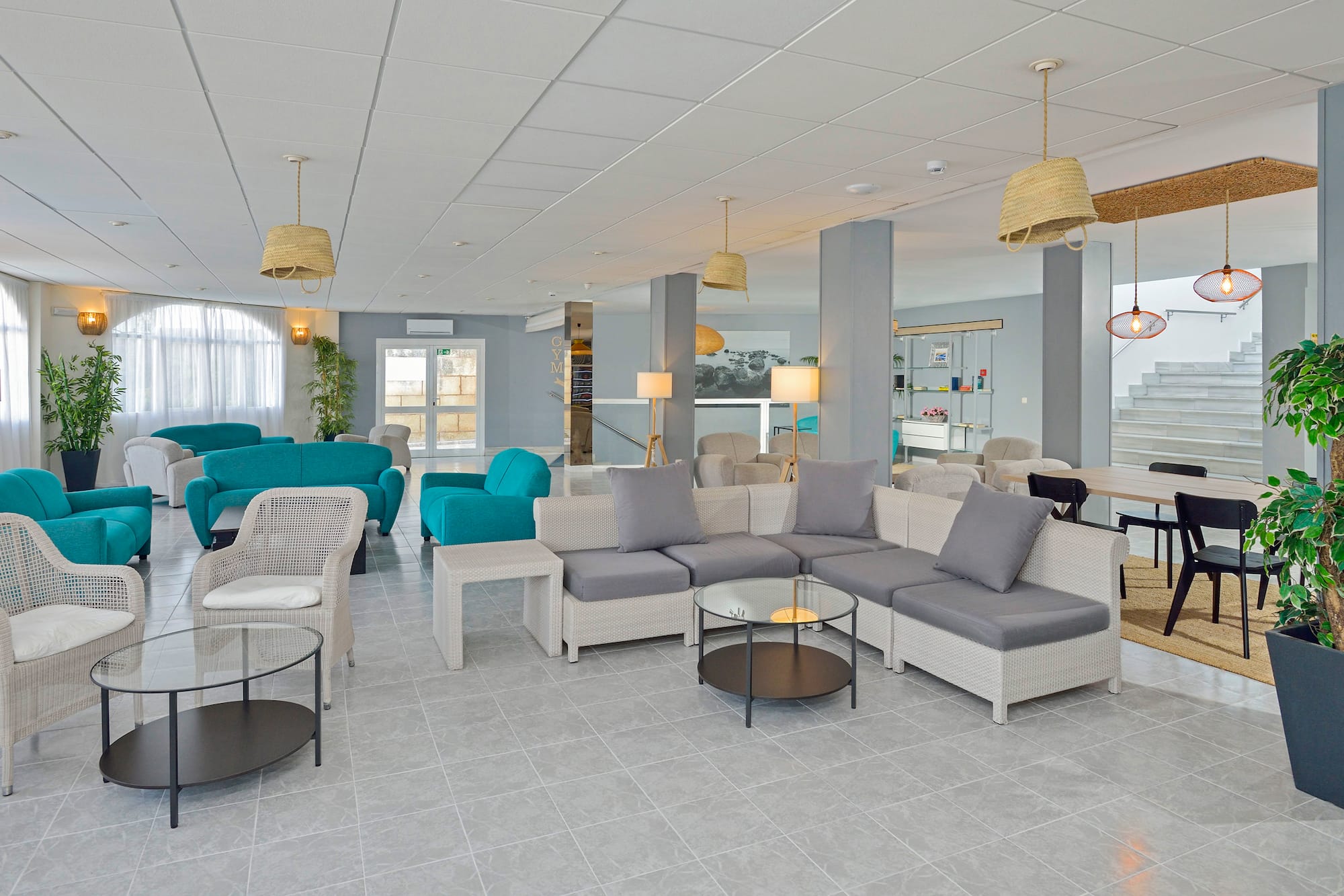Modern hotel lobby lounge with teal sofas, grey seating, and wicker chairs.