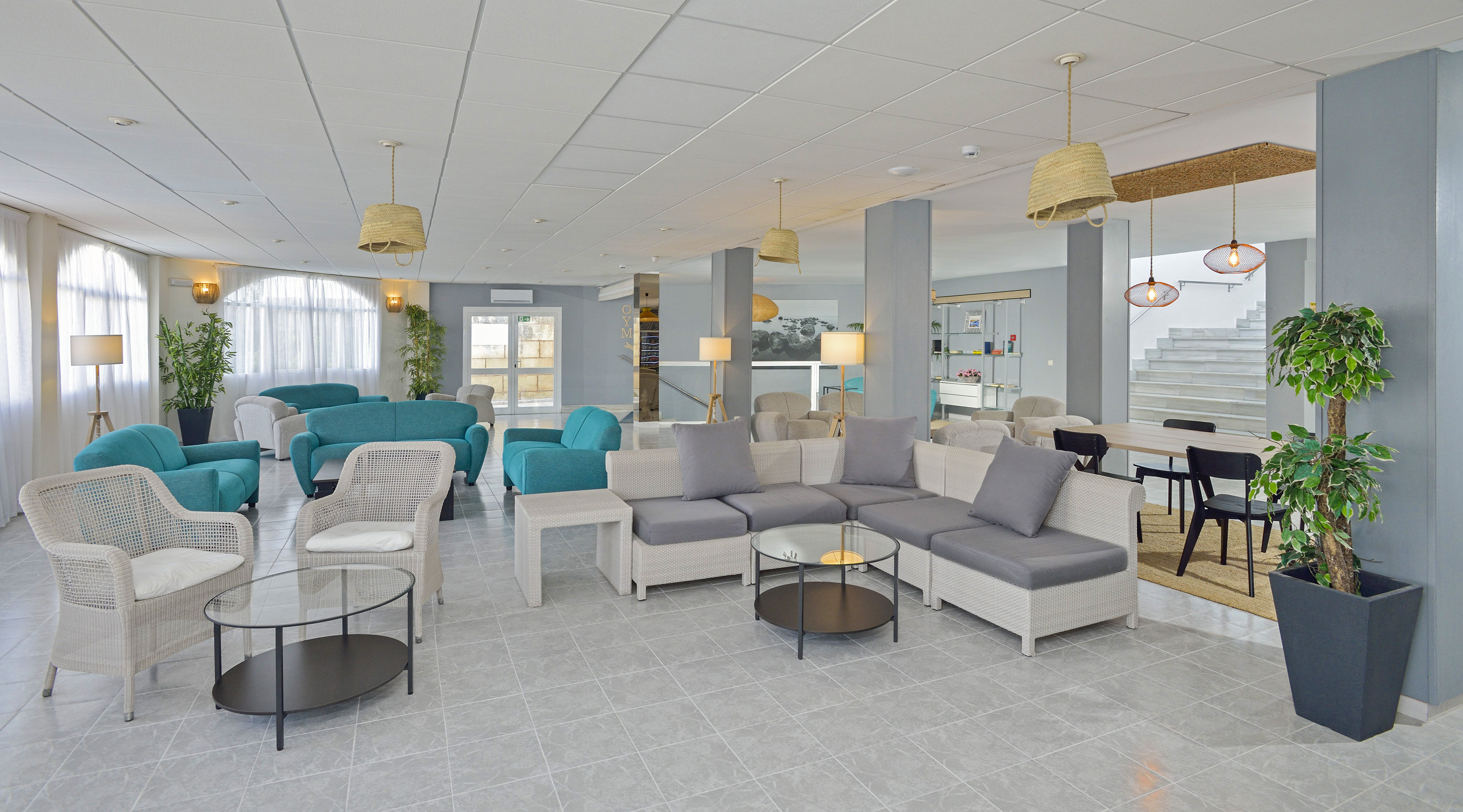 Modern hotel lobby lounge with teal sofas, grey seating, and wicker chairs.