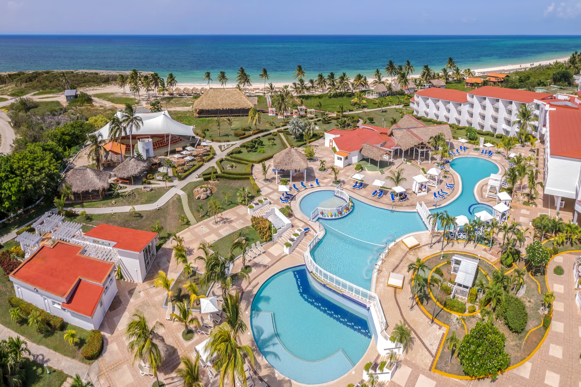 a resort with a swimming pool and a beach with Cayo Coco in the background