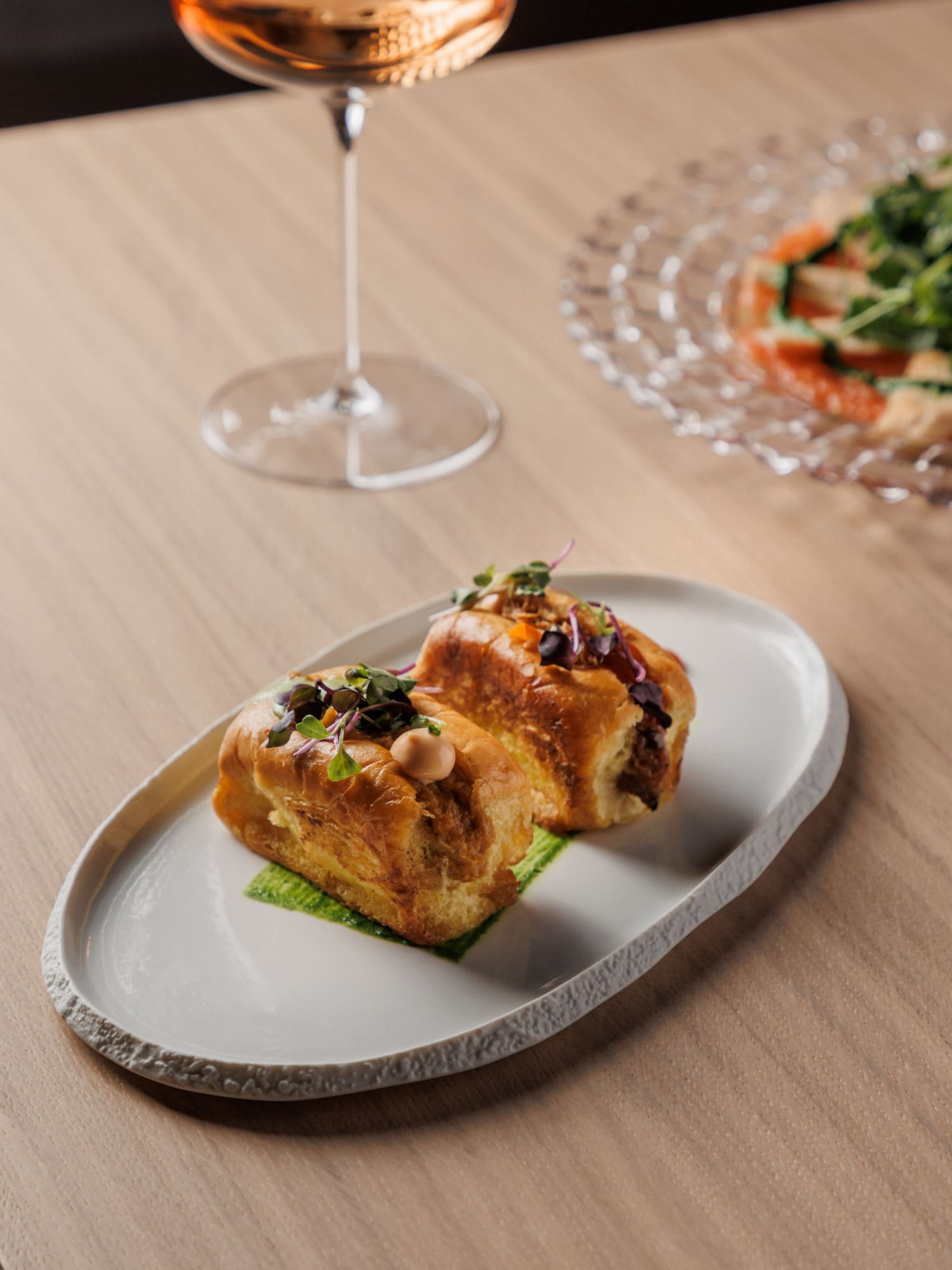 food on a plate next to a glass of wine