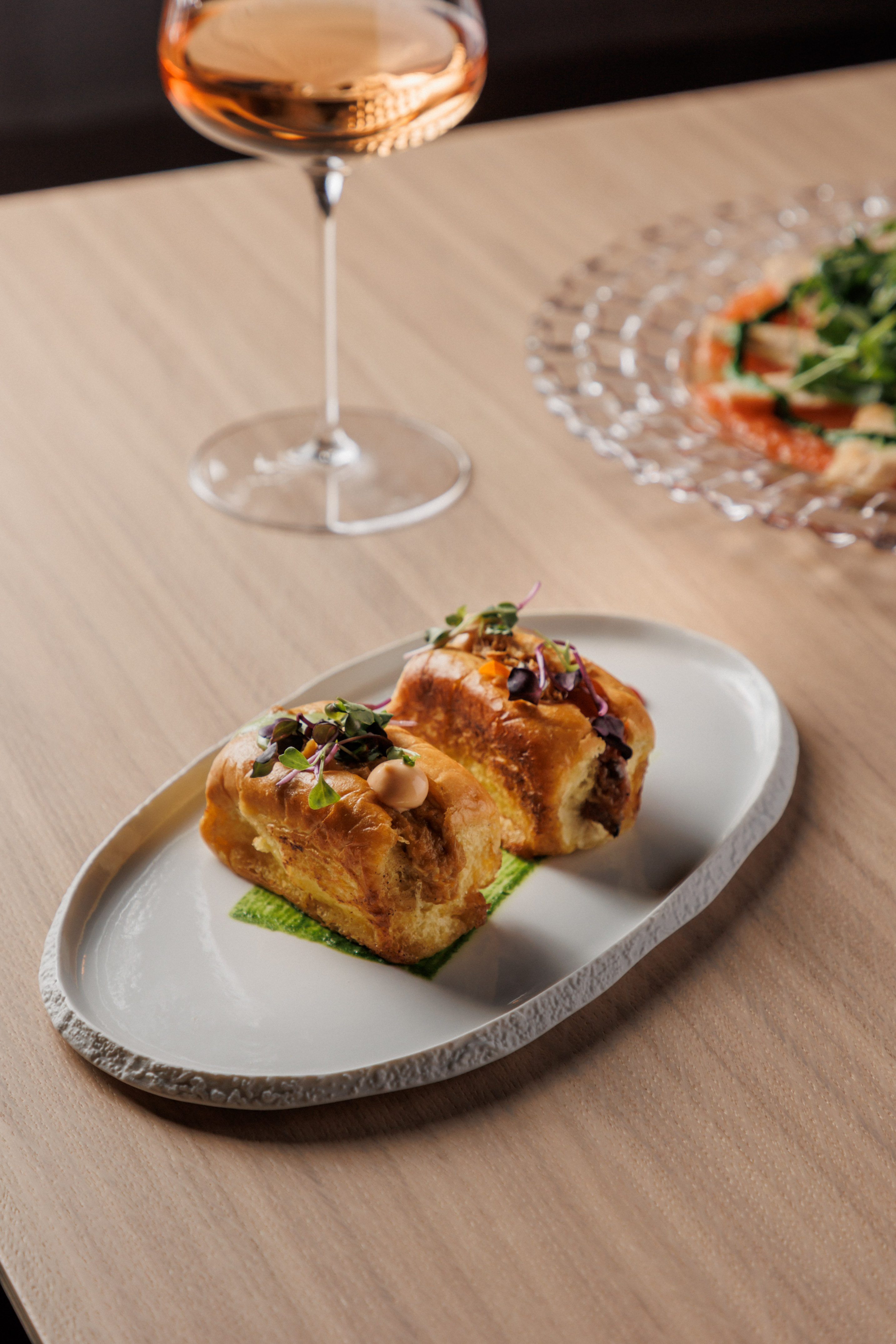 food on a plate next to a glass of wine