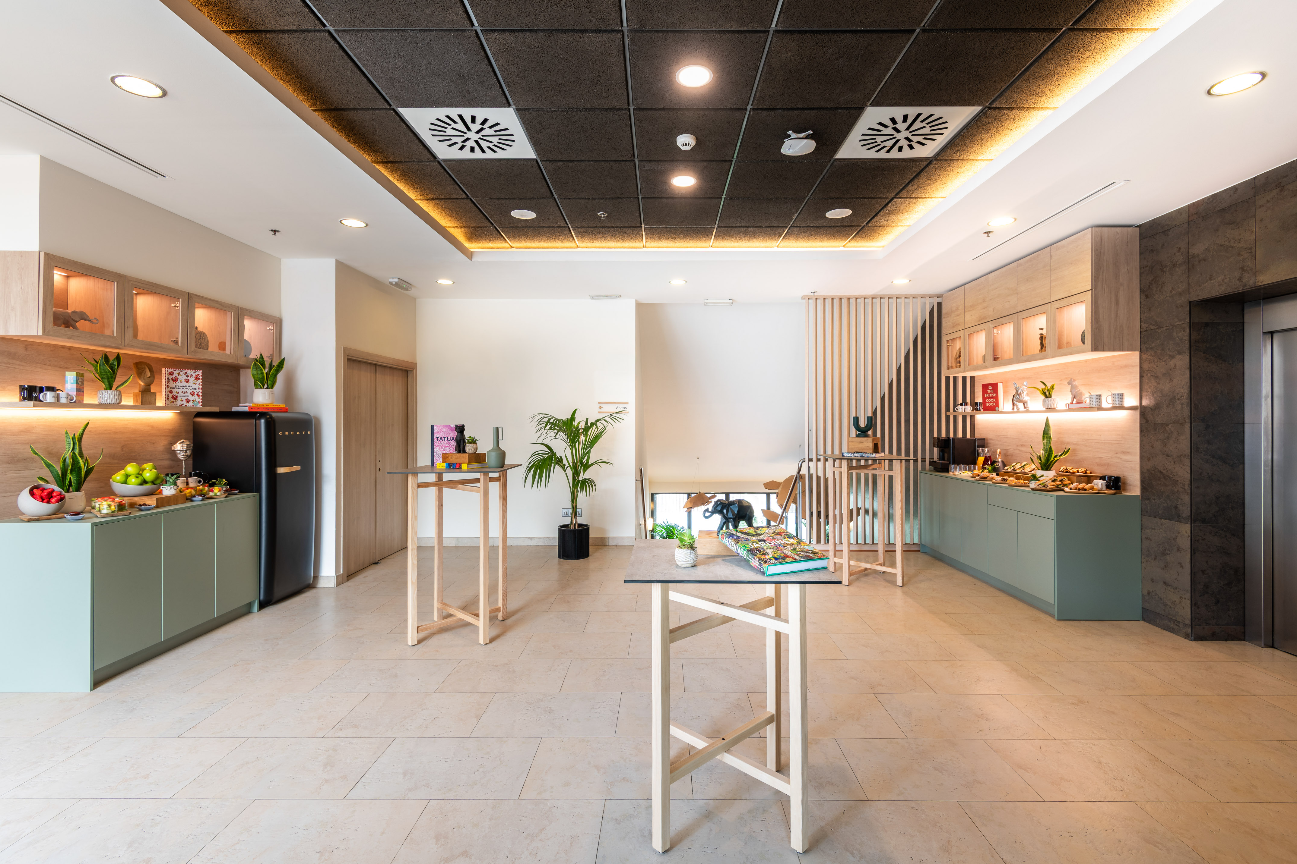 Modern hotel lobby refreshment buffet with green cabinets and wooden shelves.