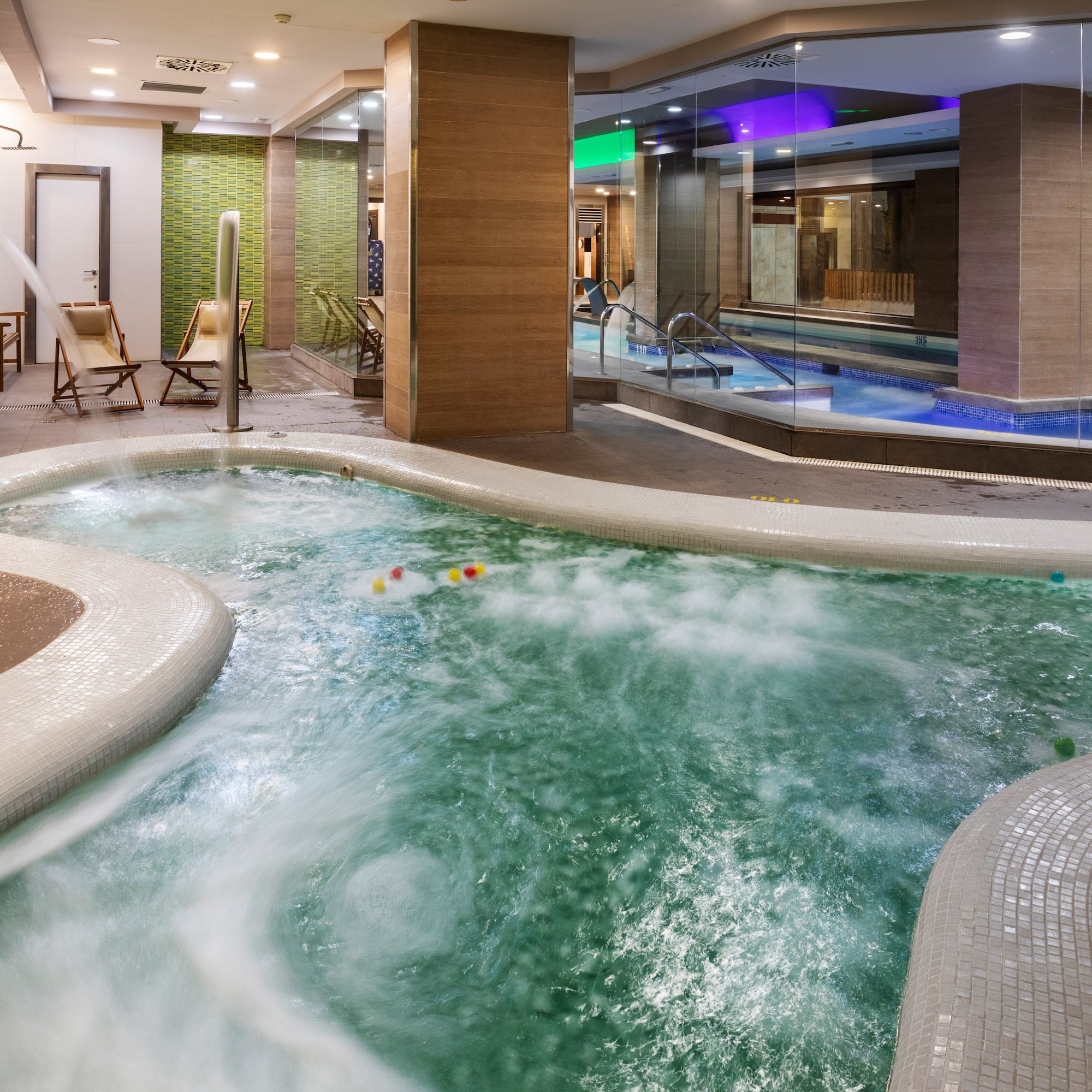Bubbling indoor jacuzzi with white tiles in a modern spa and wellness center.