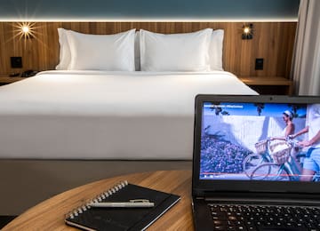 a laptop and a pen on a table in front of a bed