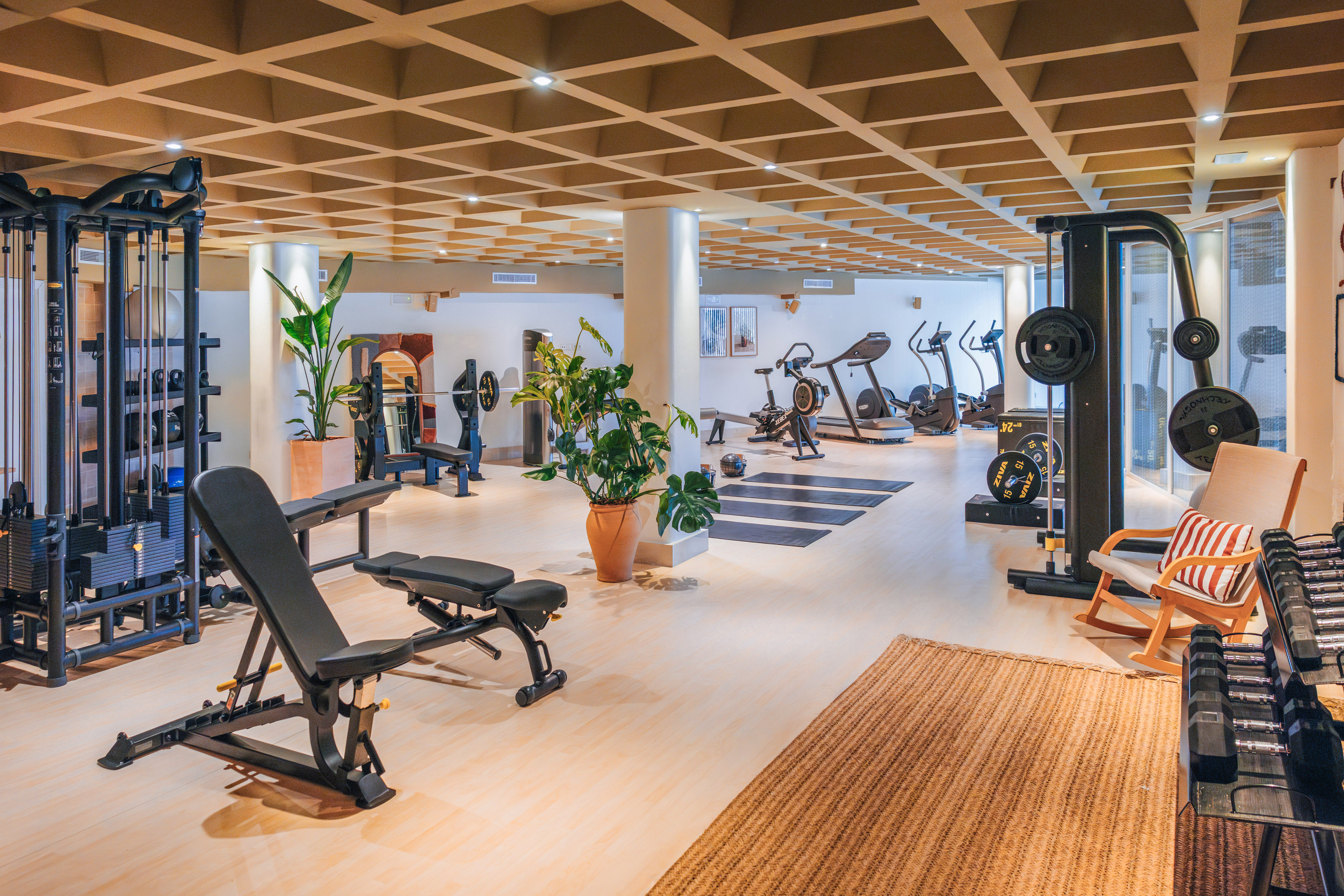 Hotel gym featuring weight racks, benches, treadmills, and rowing machine.