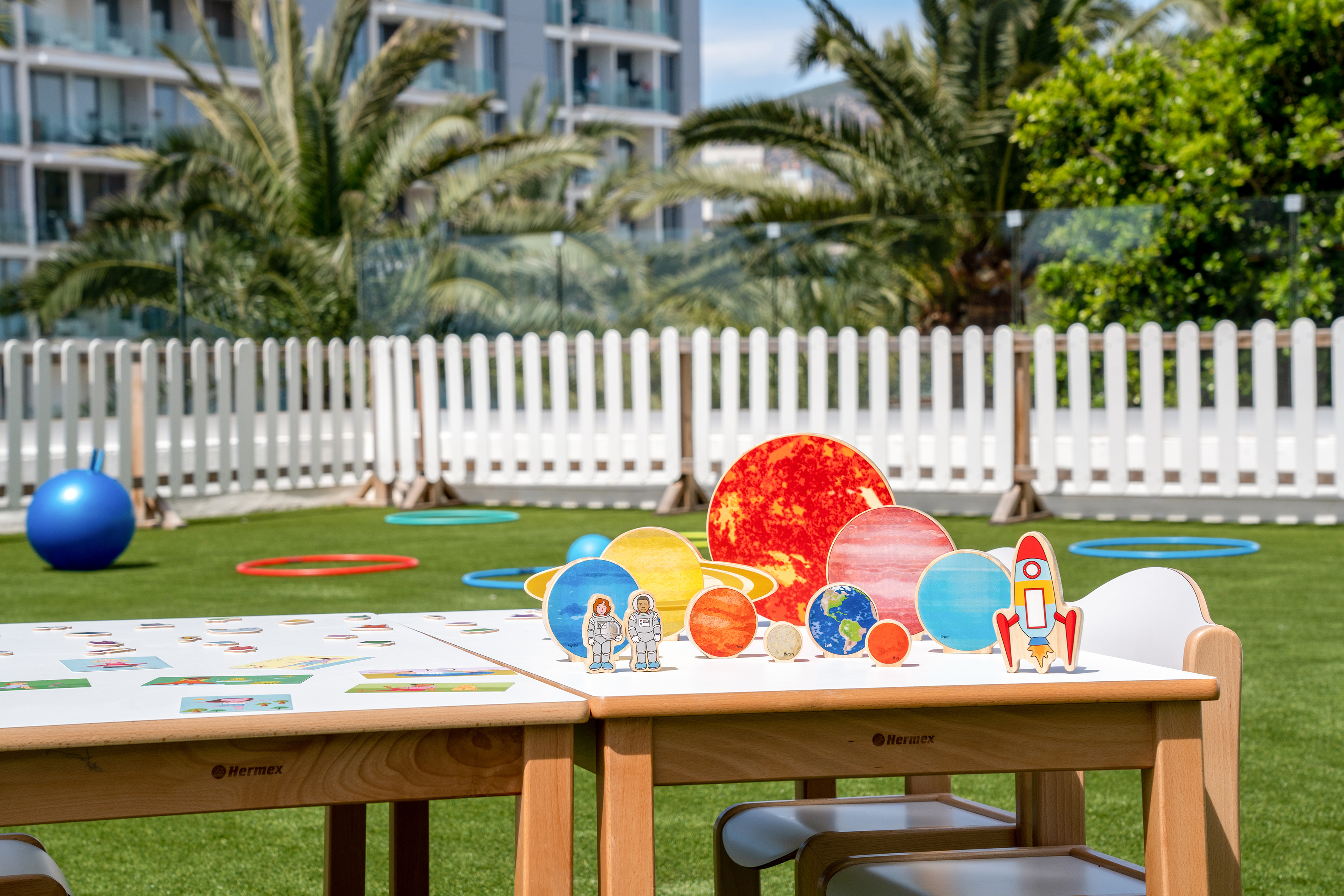 Kids' outdoor play area with space planet, astronaut, and rocket toys on table.