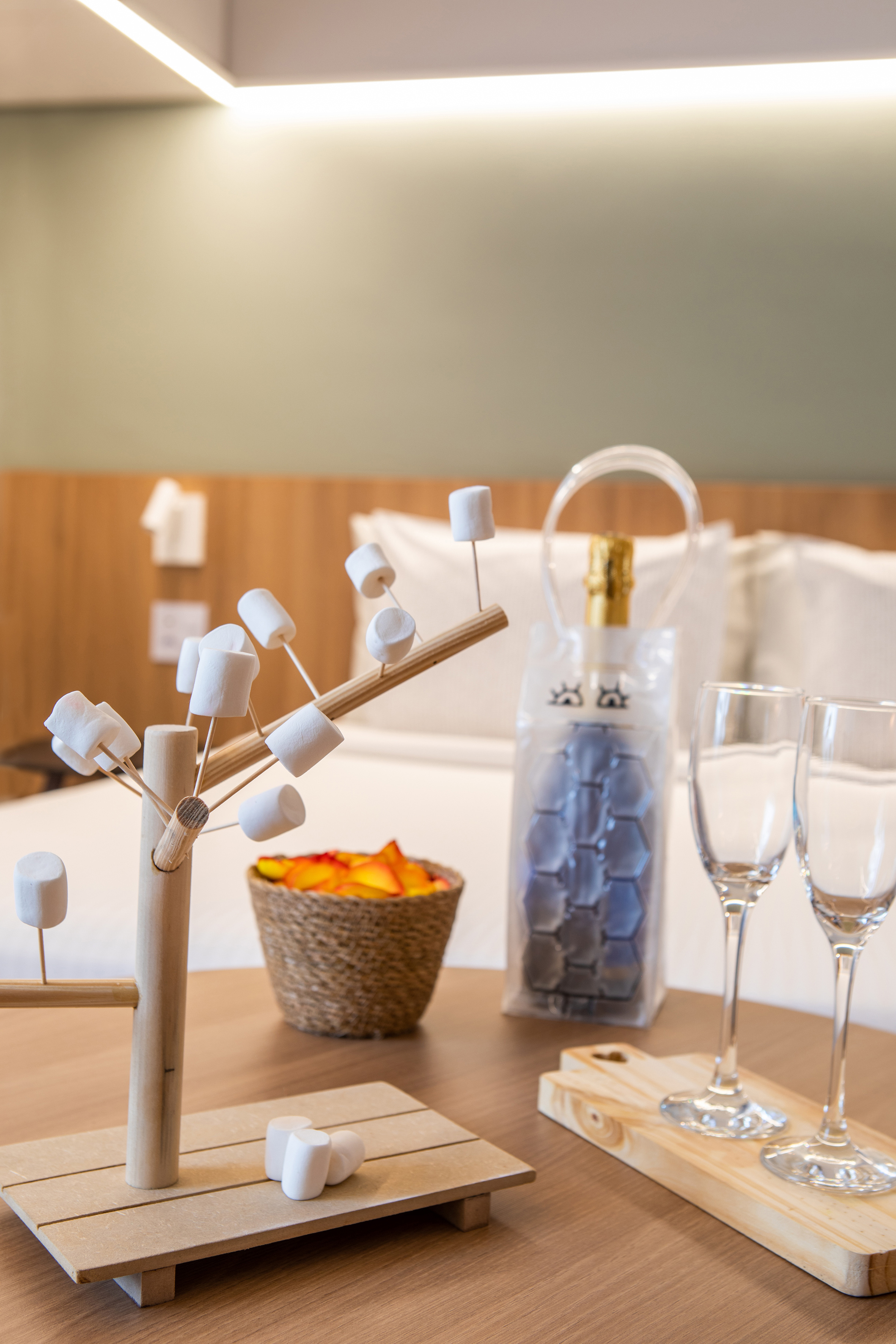 Hotel room setup: marshmallow stand, sparkling wine, flutes, rose petals.