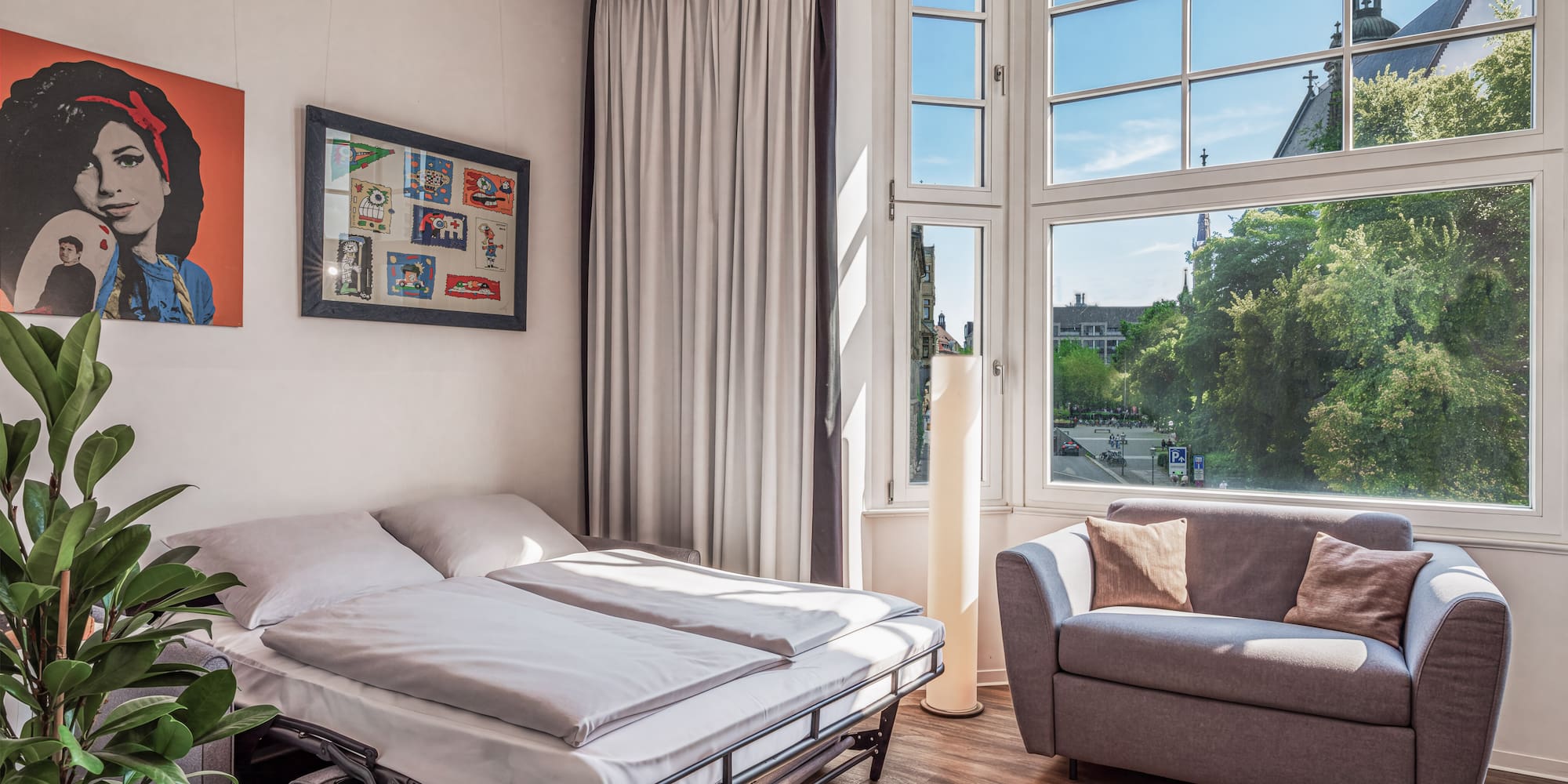 Modern studio with sofa bed, gray couch, and city view window.