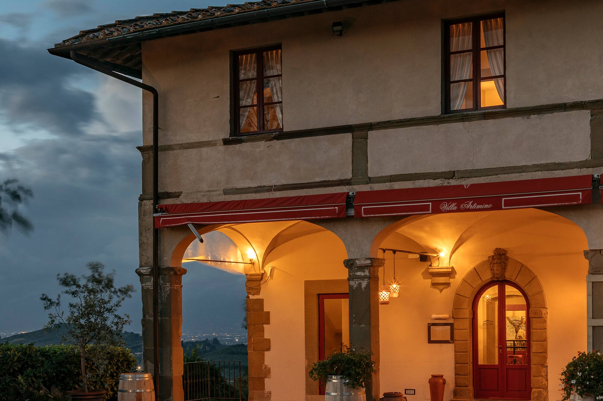 Tuscan Villa Artimino glowing with warm lights at dusk, arched entrance.
