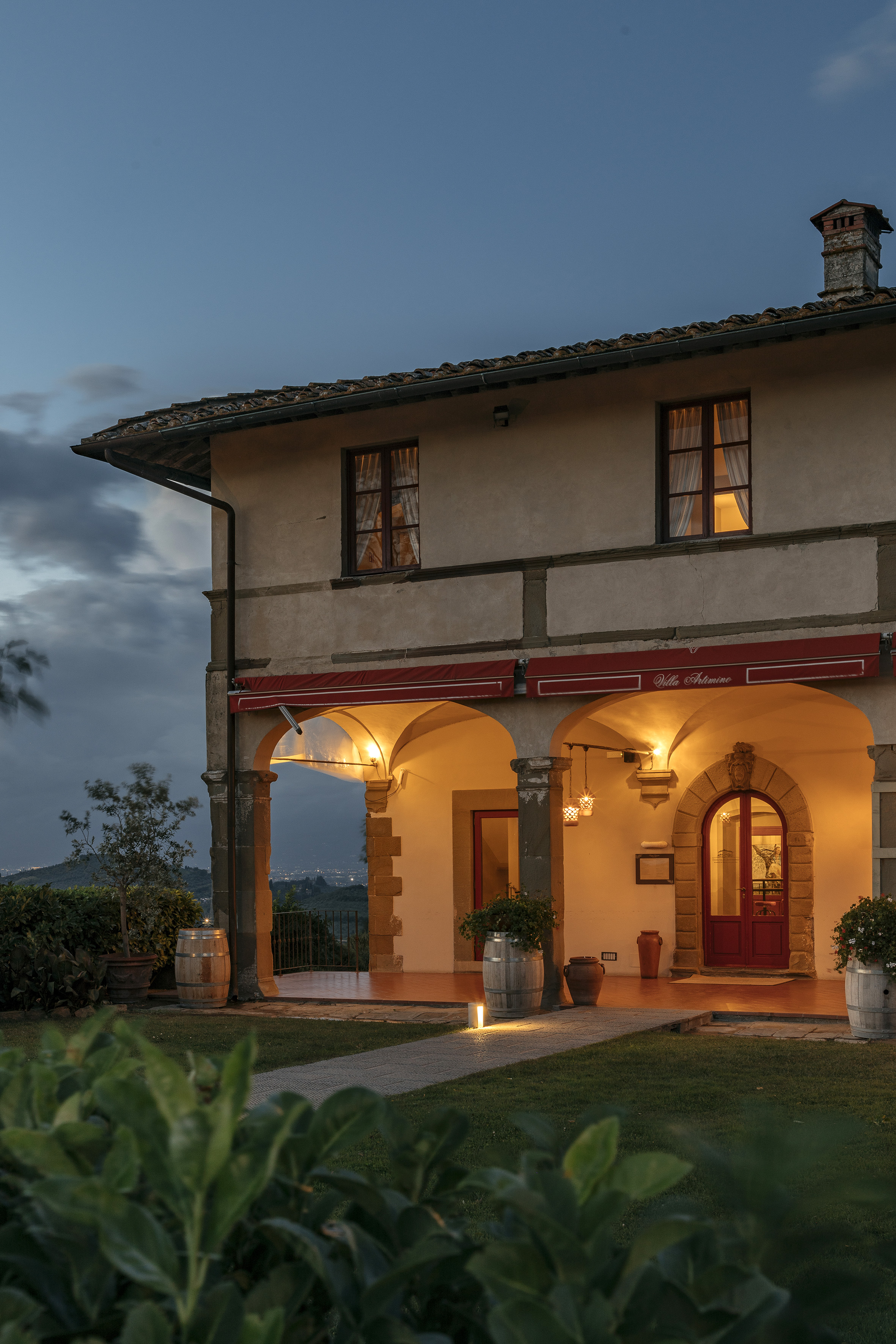 Tuscan Villa Artimino glowing with warm lights at dusk, arched entrance.