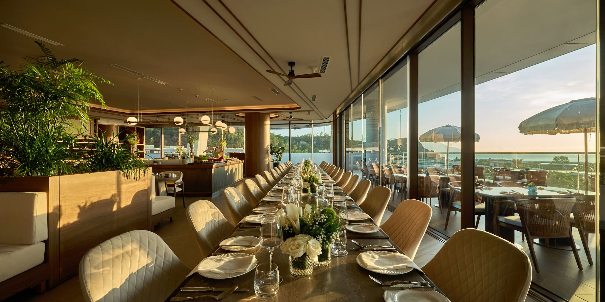 a long table with white chairs and plates