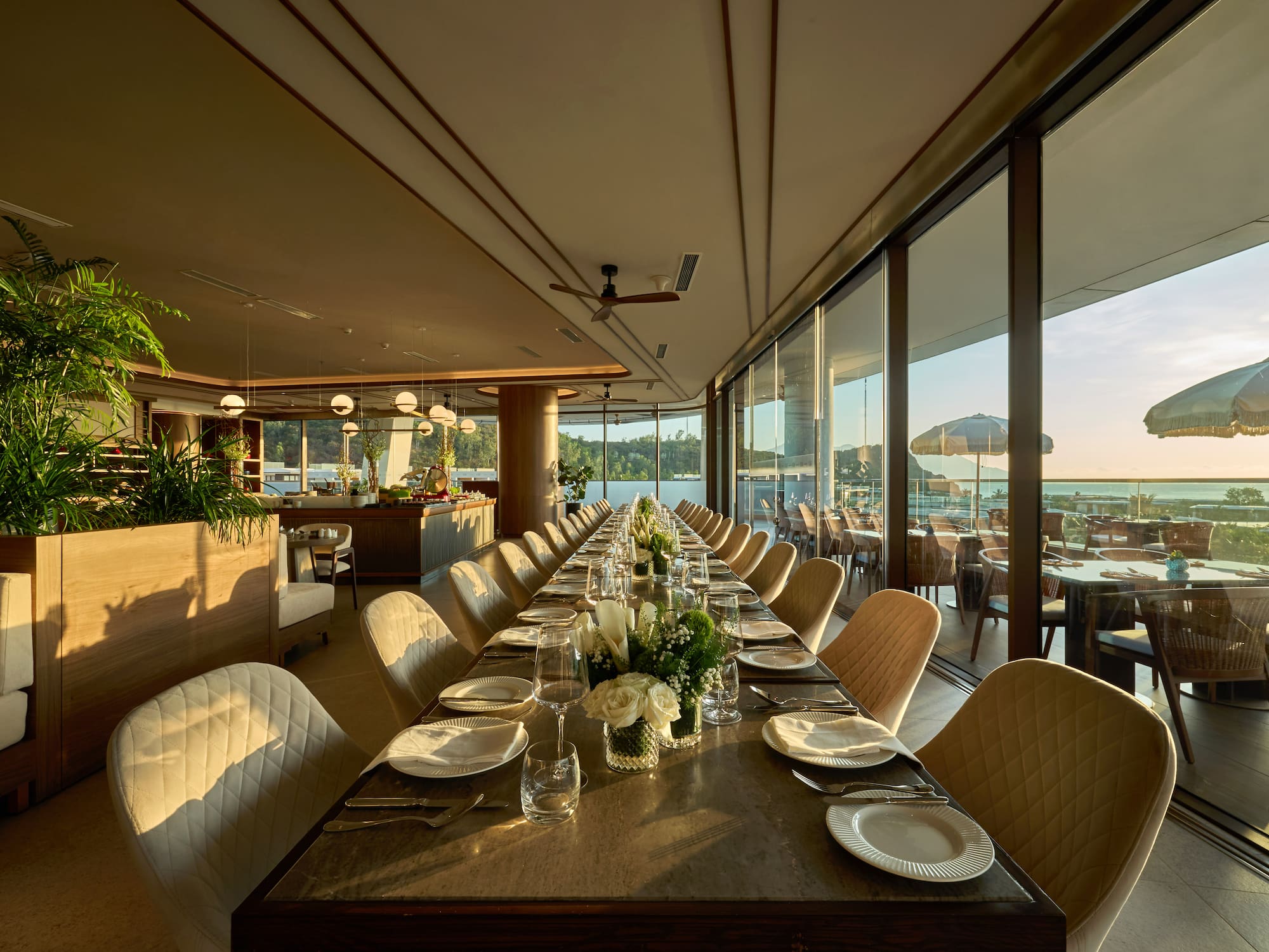 a long table with white chairs and plates