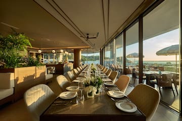 a long table with white chairs and plates