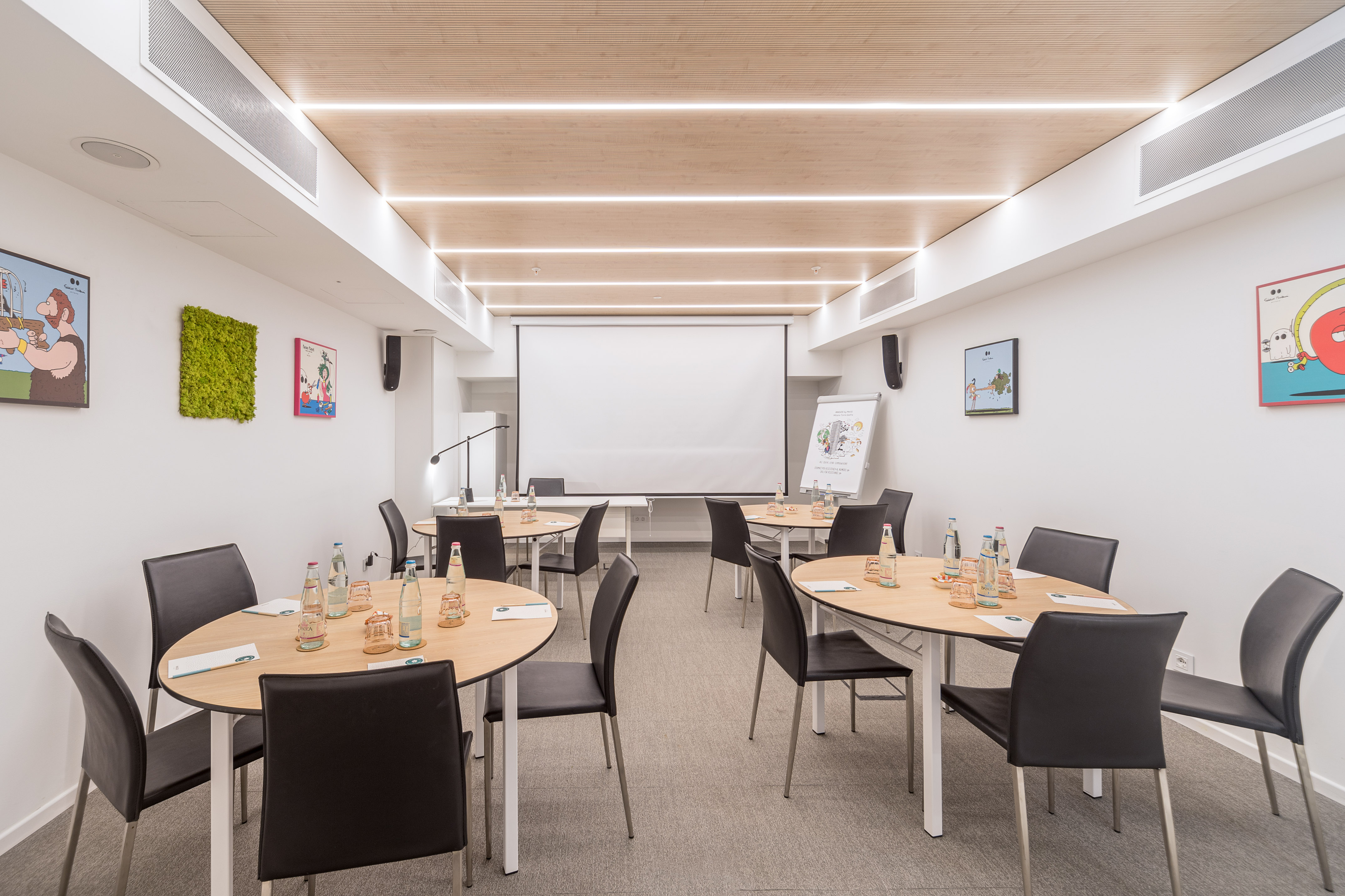 Modern meeting room with small tables, projector, and bright wood ceiling.