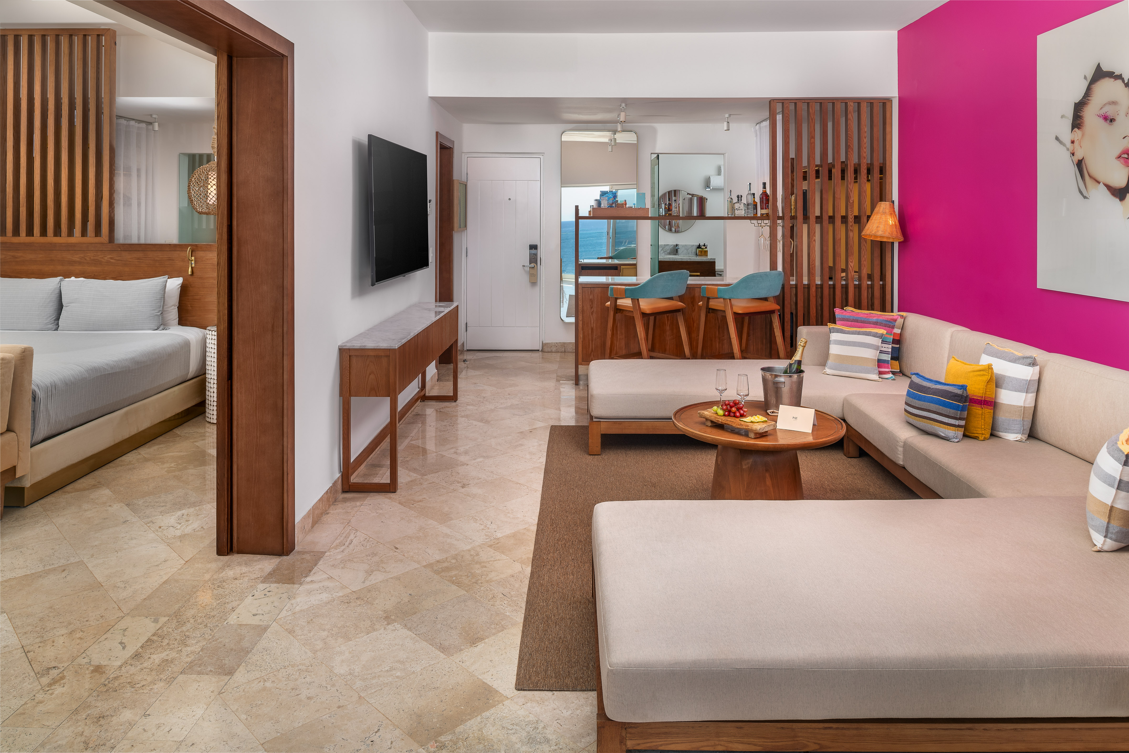 Vibrant resort room with living area, bedroom, and ocean view bar.