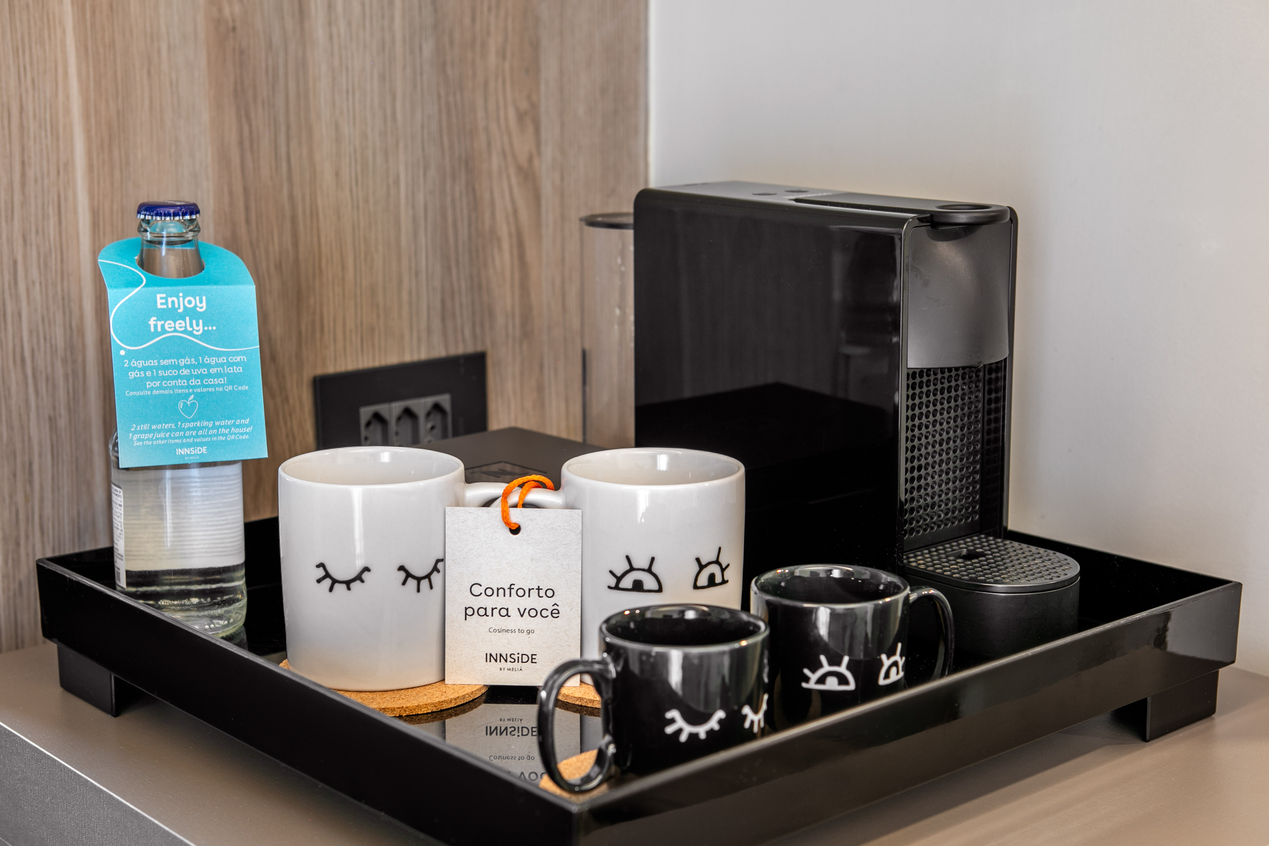 Hotel coffee station: Nespresso machine, complimentary water, eye-design mugs.