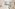 Bright hotel room with two beds, large balcony overlooking ocean and cliffs.