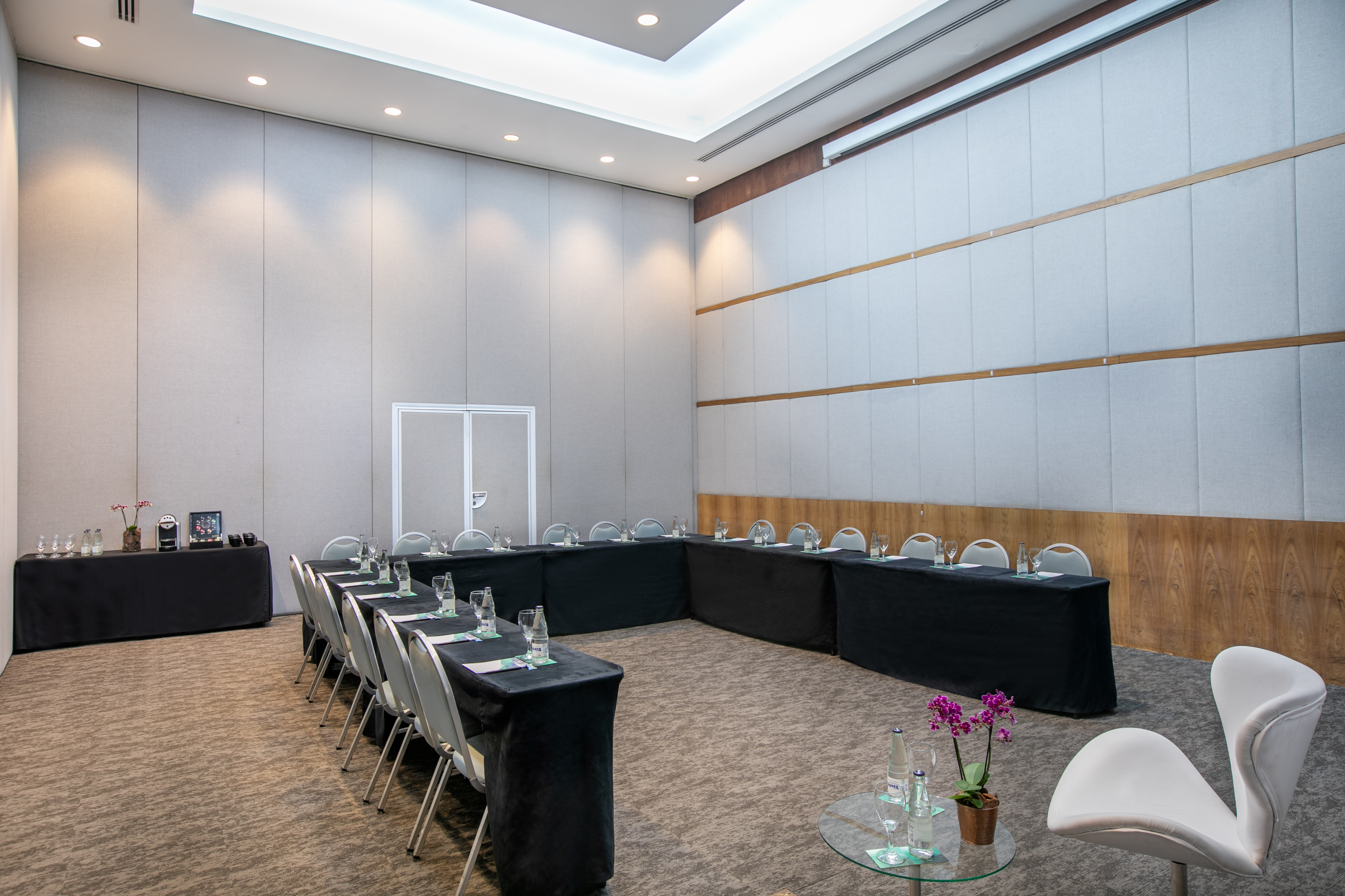 Modern conference room with U-shape table setup and refreshment station.