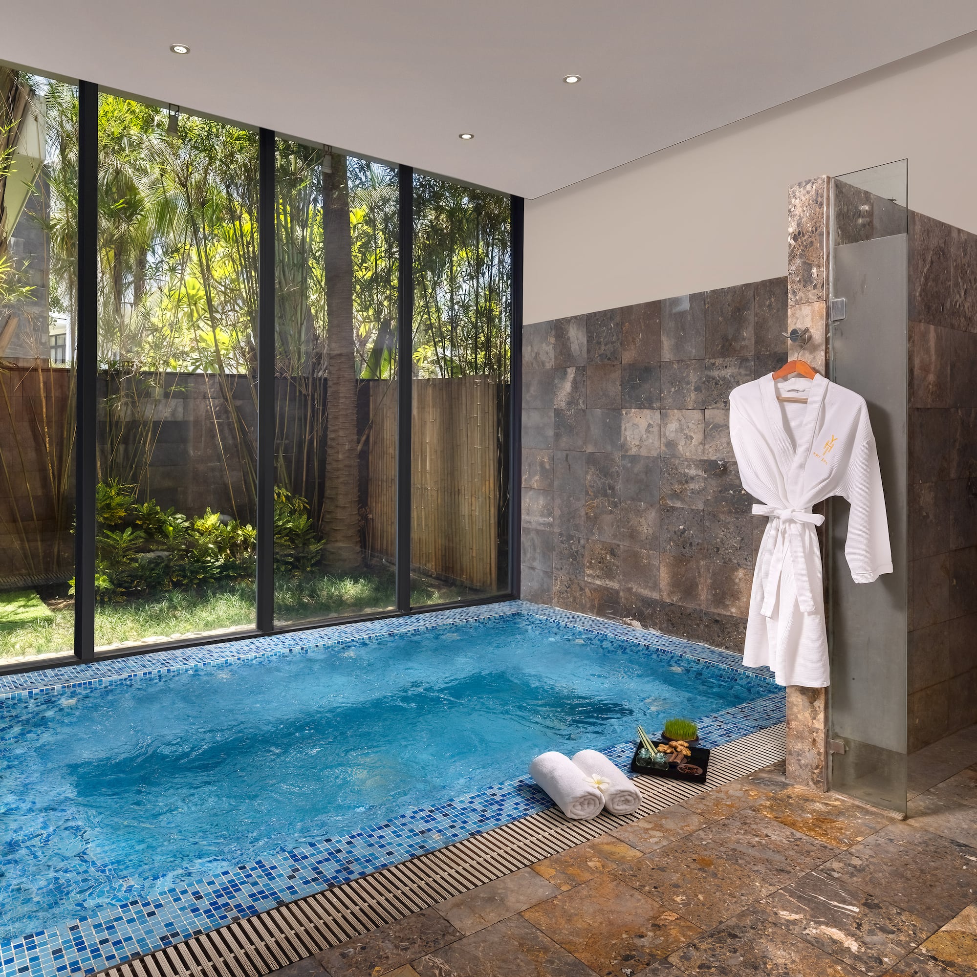 a pool with a bathrobe and towels in a room with windows