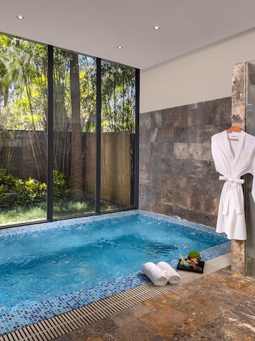 a pool with a bathrobe and towels in a room with windows