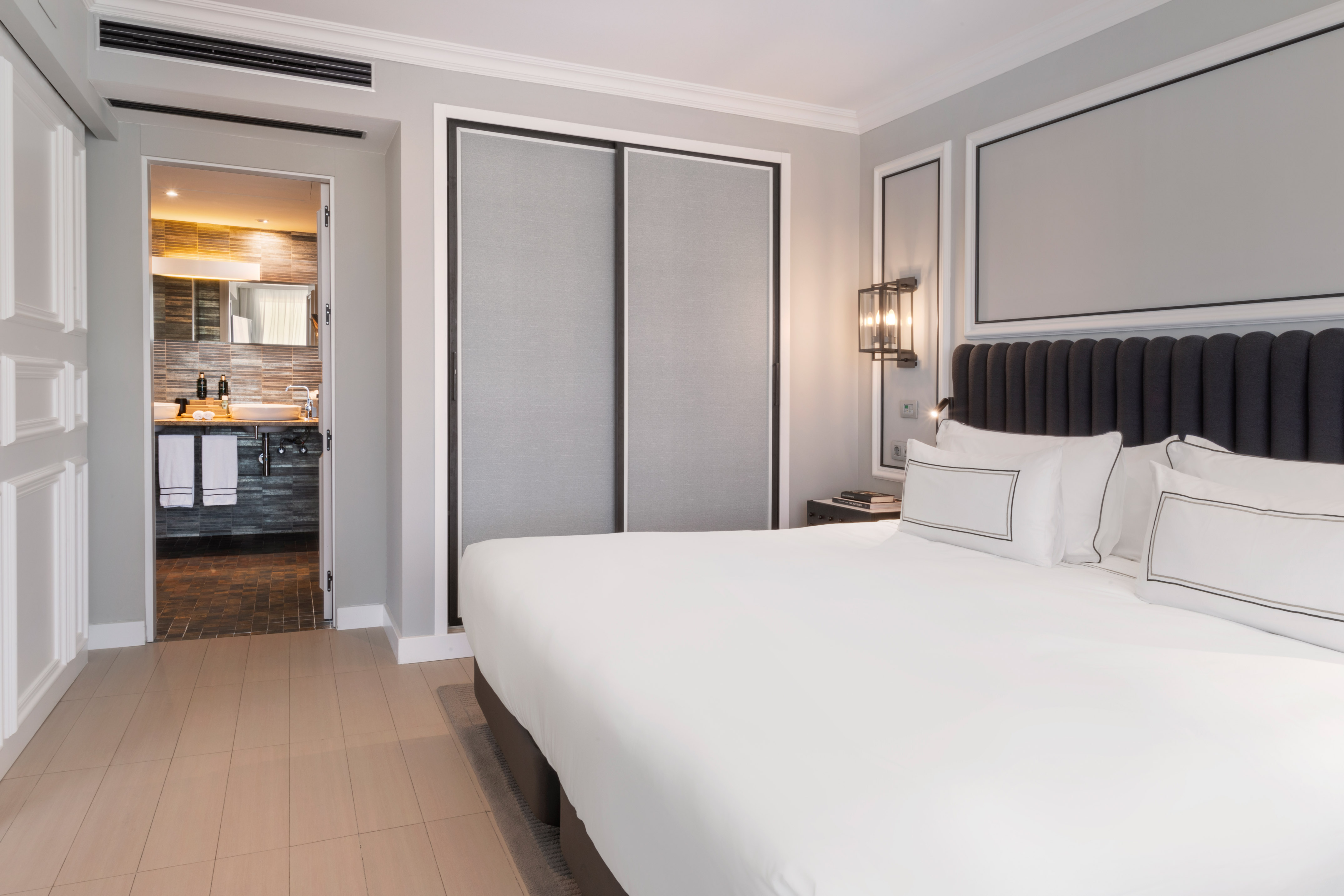 Modern hotel bedroom suite with king bed, closet, and bathroom access.