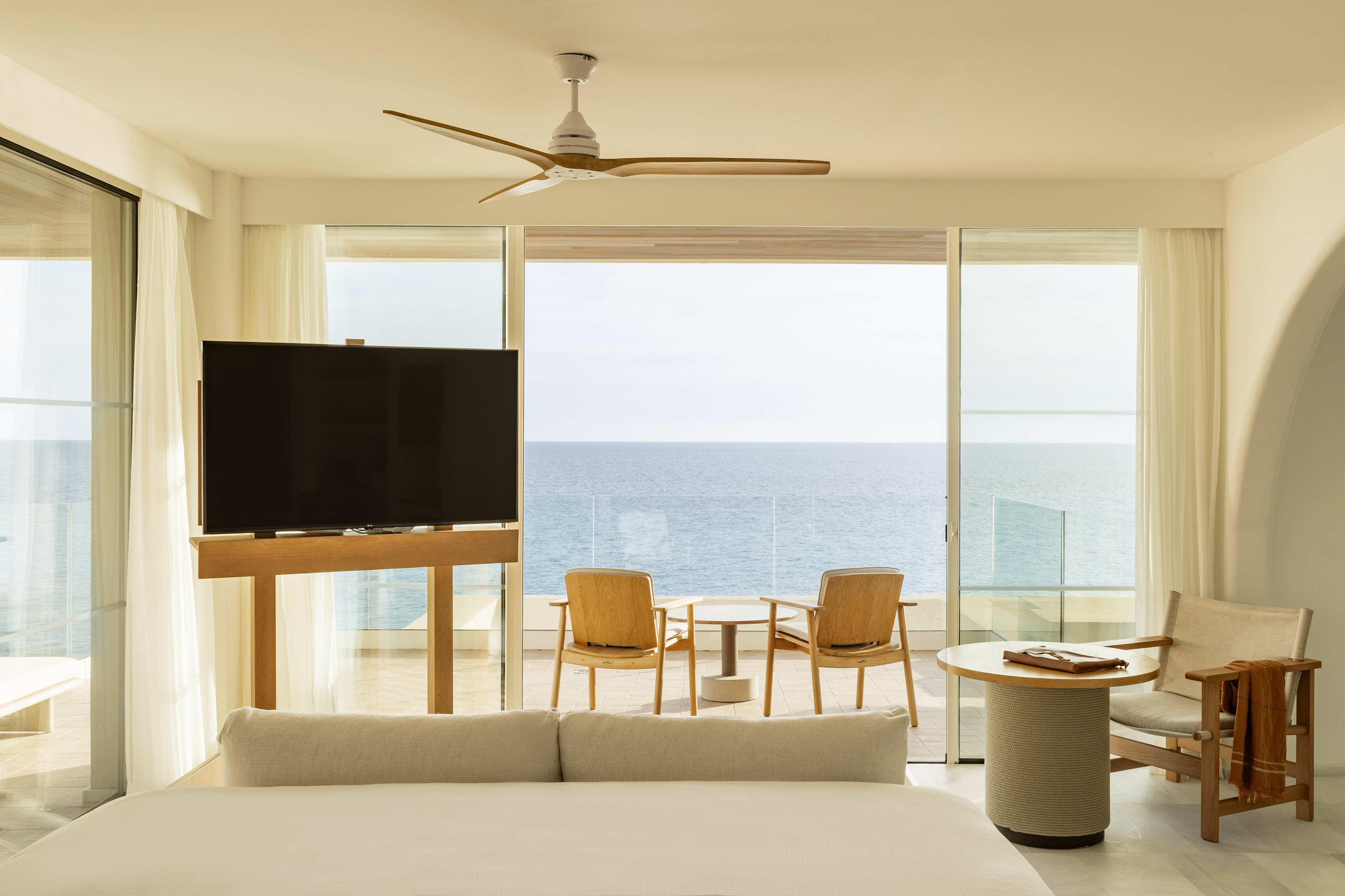 Bright modern hotel room with ocean view, private balcony, and sleek decor.