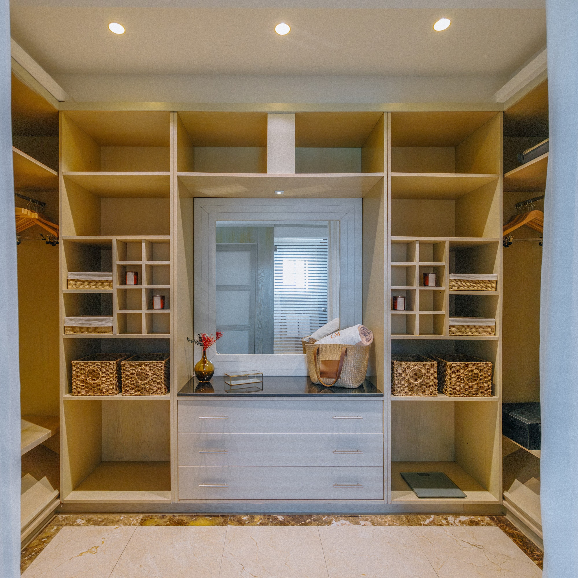 Elegant walk-in closet with custom wood shelves, central mirror, and organized storage.