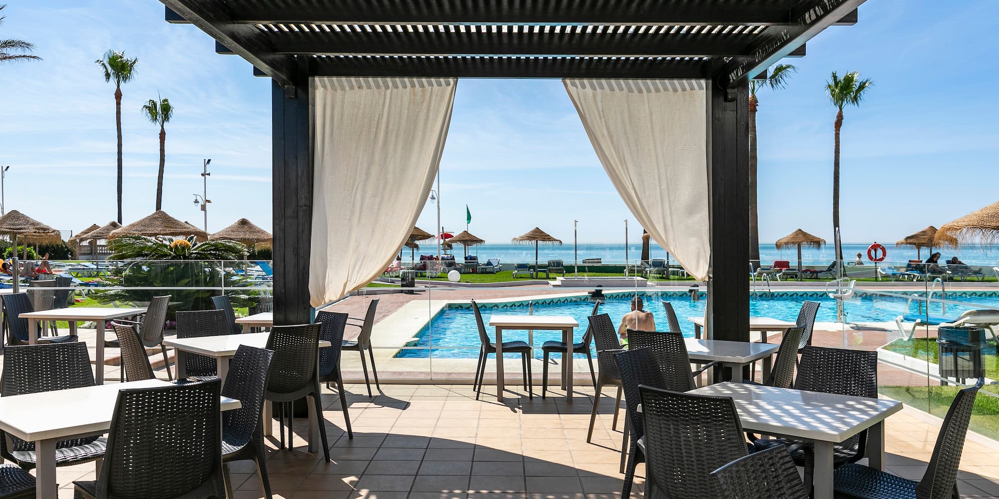 a pool with a covered patio with tables and chairs