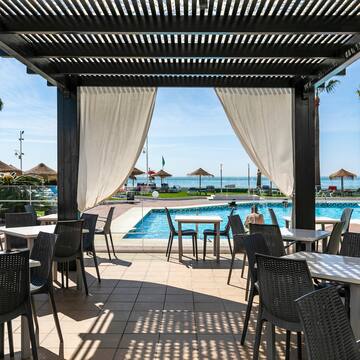 a pool with a covered patio with tables and chairs