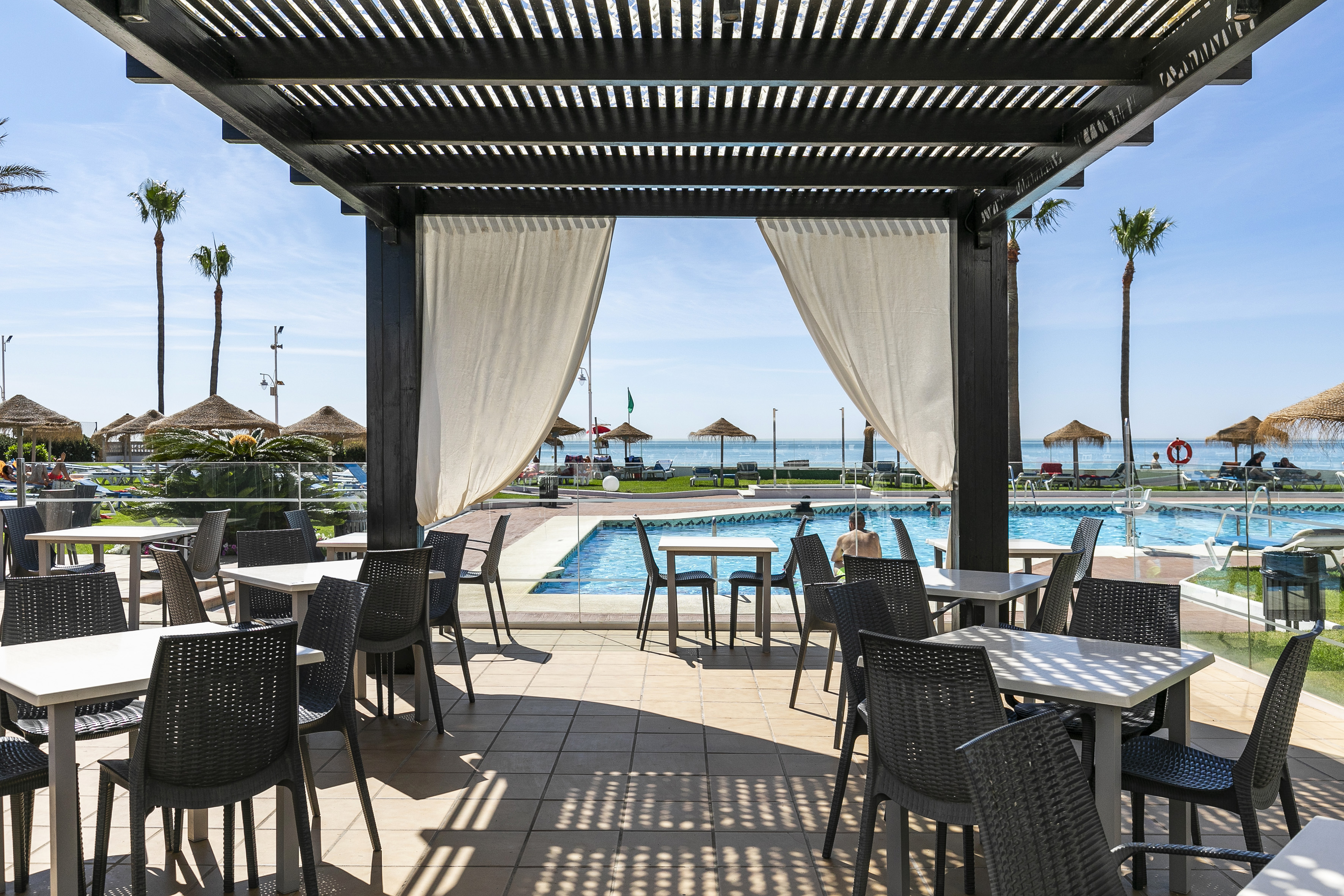 a pool with a covered patio with tables and chairs