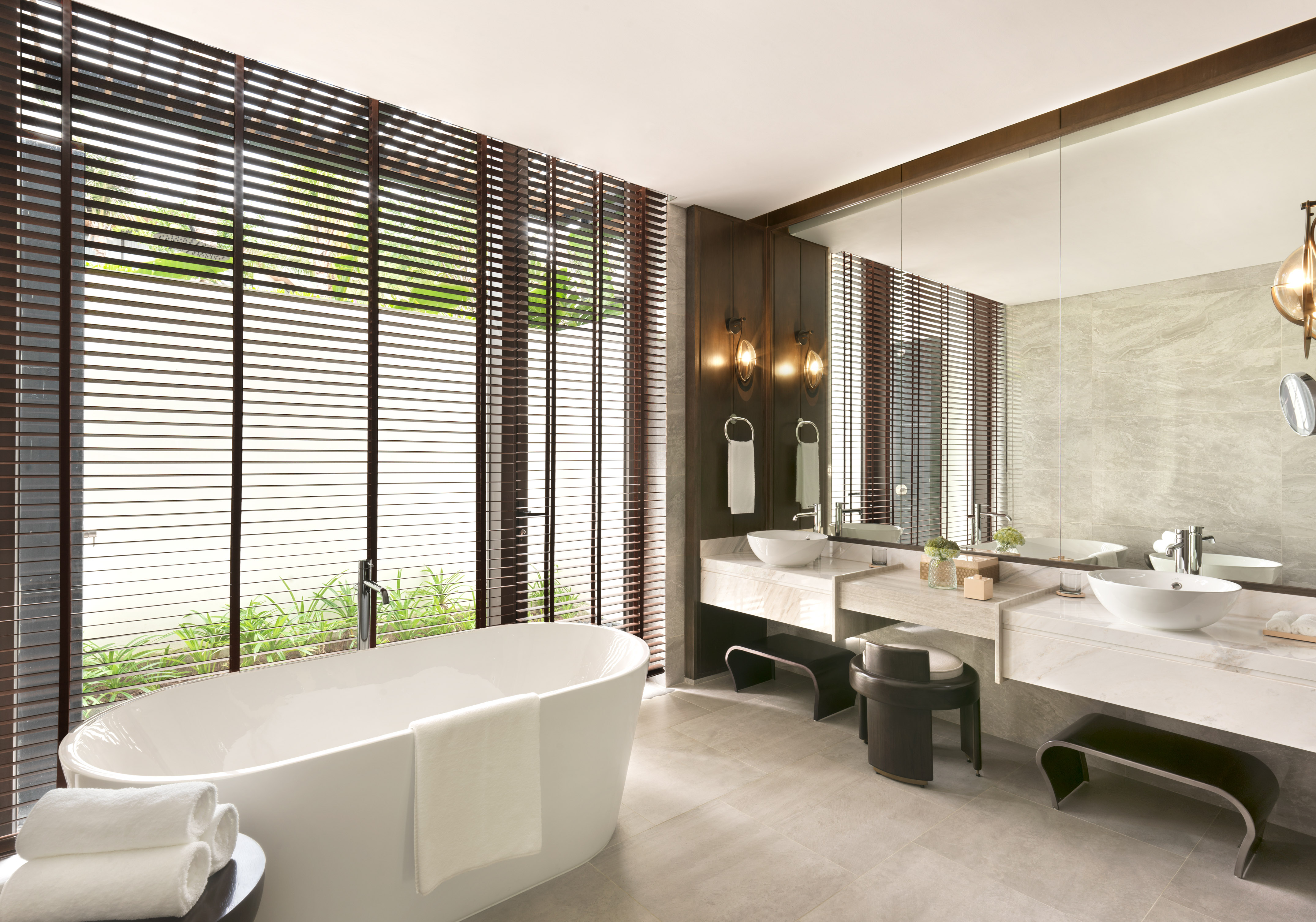 Modern luxury bathroom with freestanding tub, double vanity, and wooden privacy blinds.