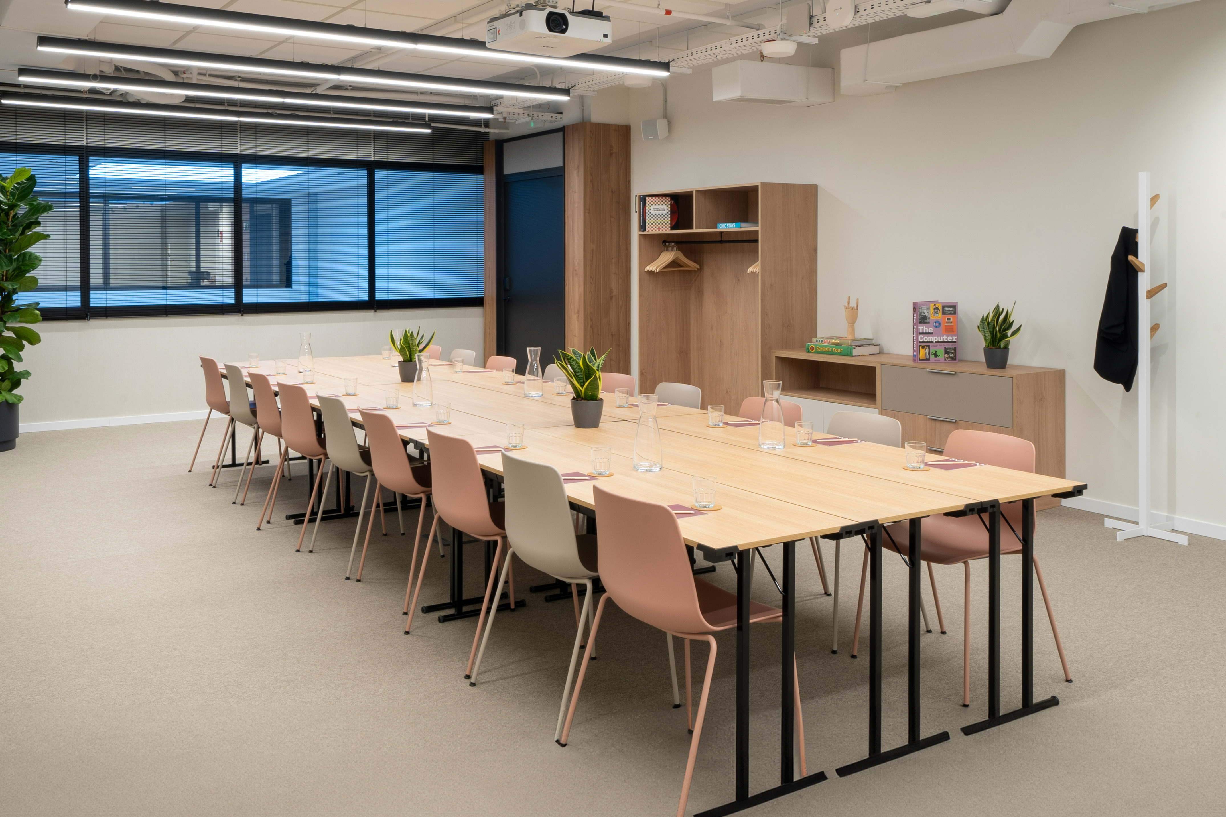 Modern conference room with long table, chairs, projector, and window.