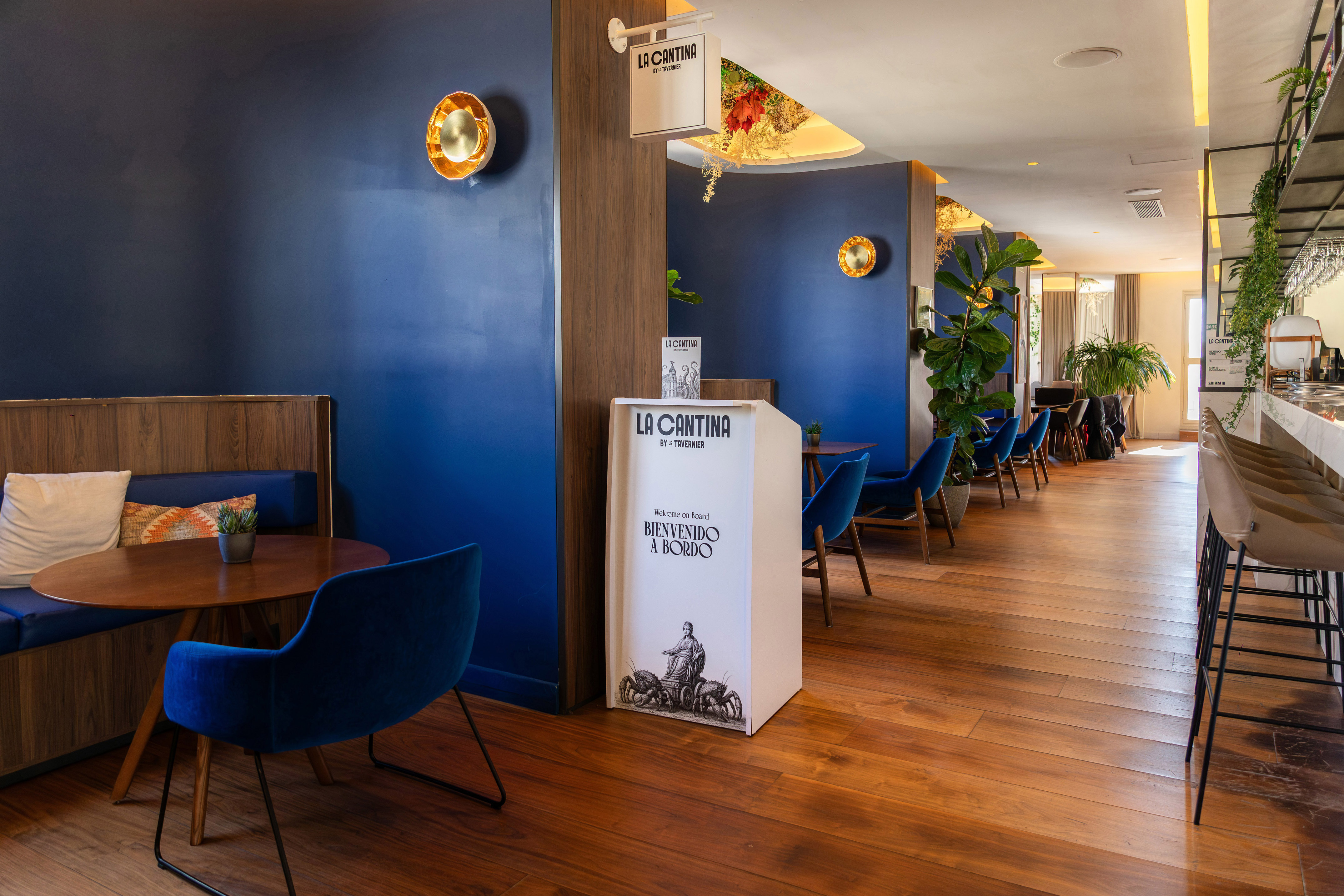 La Cantina restaurant interior: blue walls, wooden floor, velvet chairs, bar.