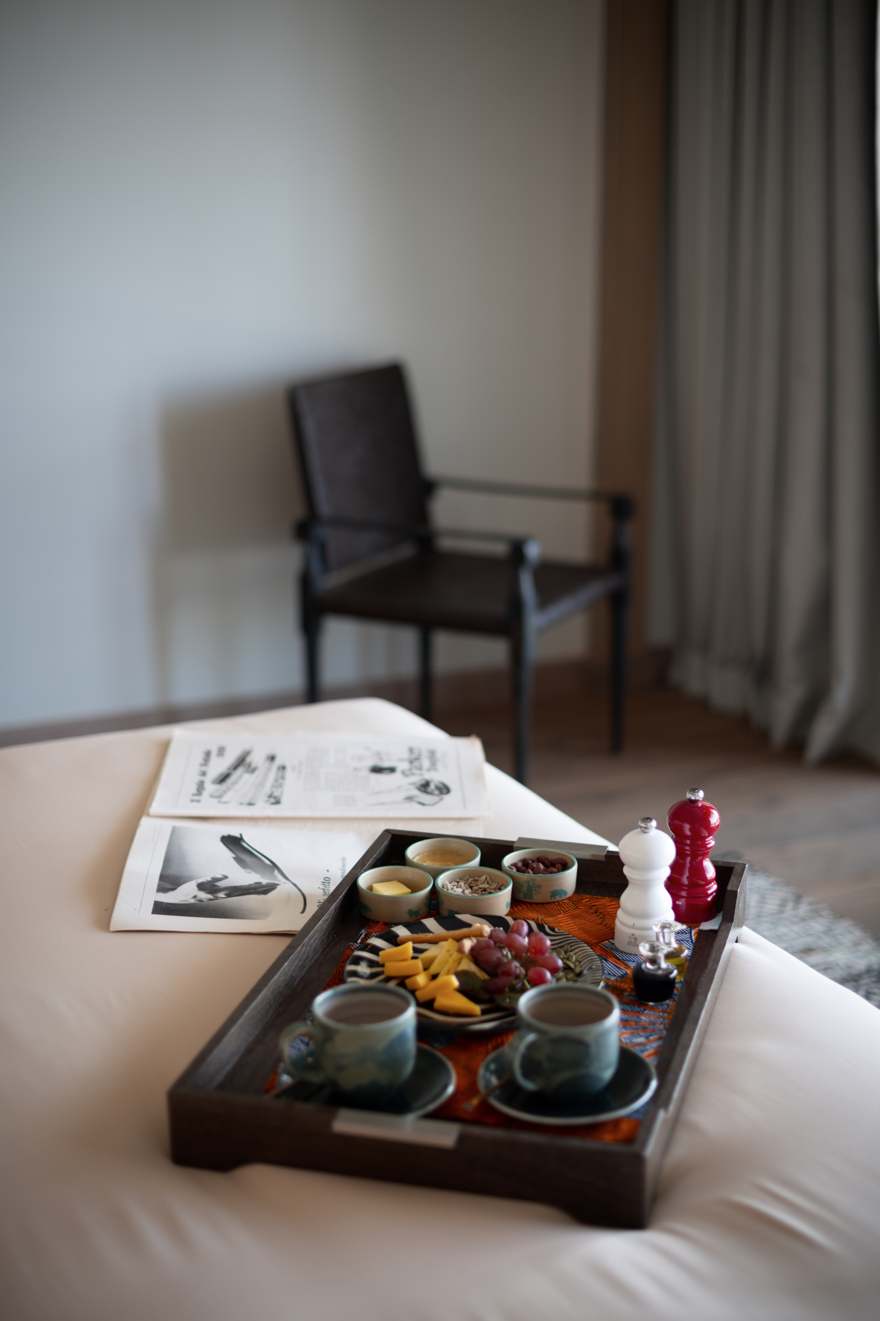 Room service breakfast in bed with coffee, fruit, cheese, and newspaper.