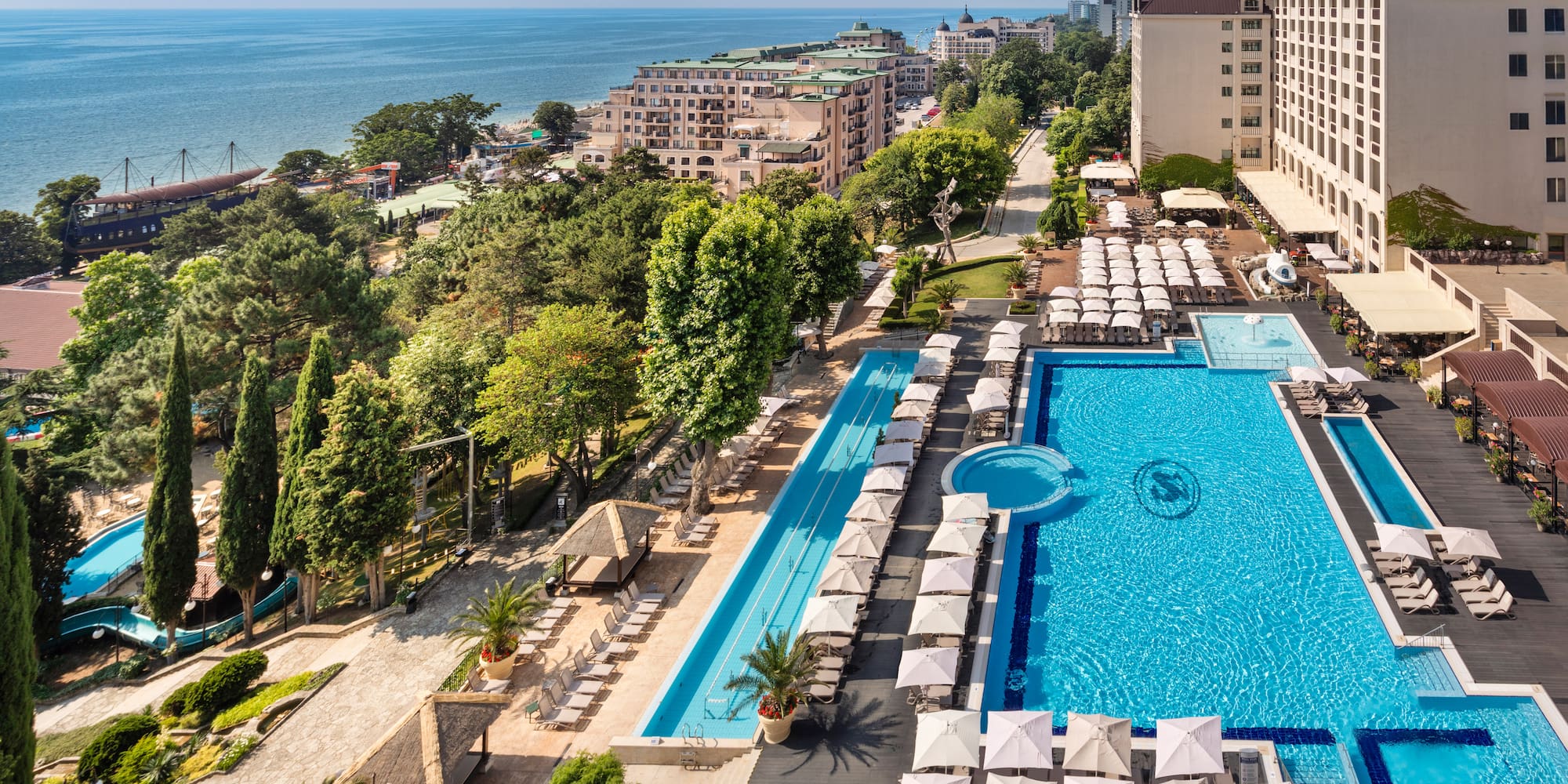 a swimming pool and a large building with trees and buildings