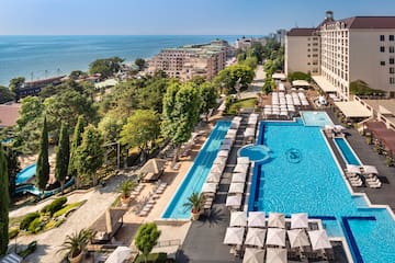 a swimming pool and a large building with trees and buildings