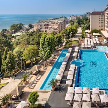a swimming pool and a large building with trees and buildings