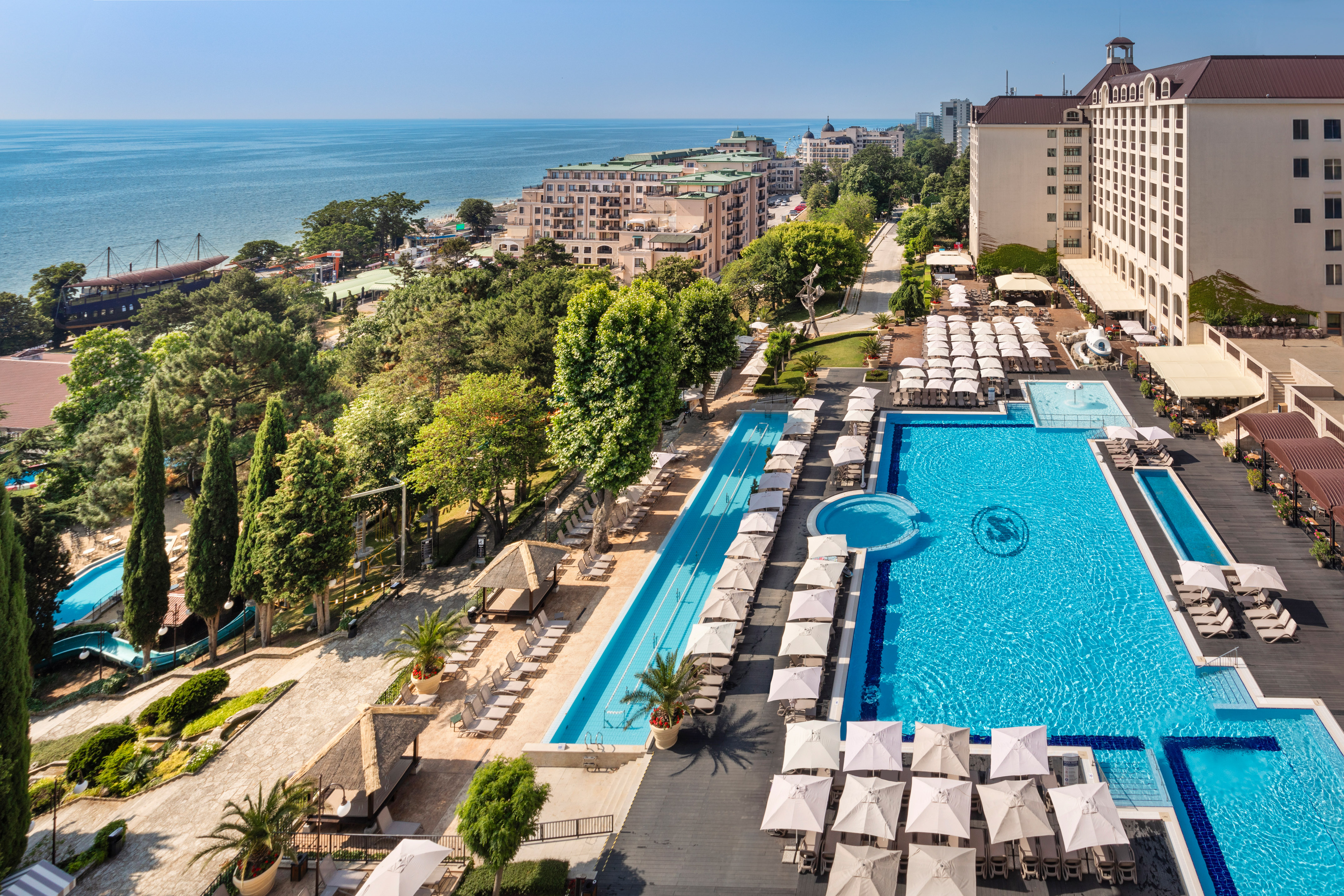 a swimming pool and a large building with trees and buildings