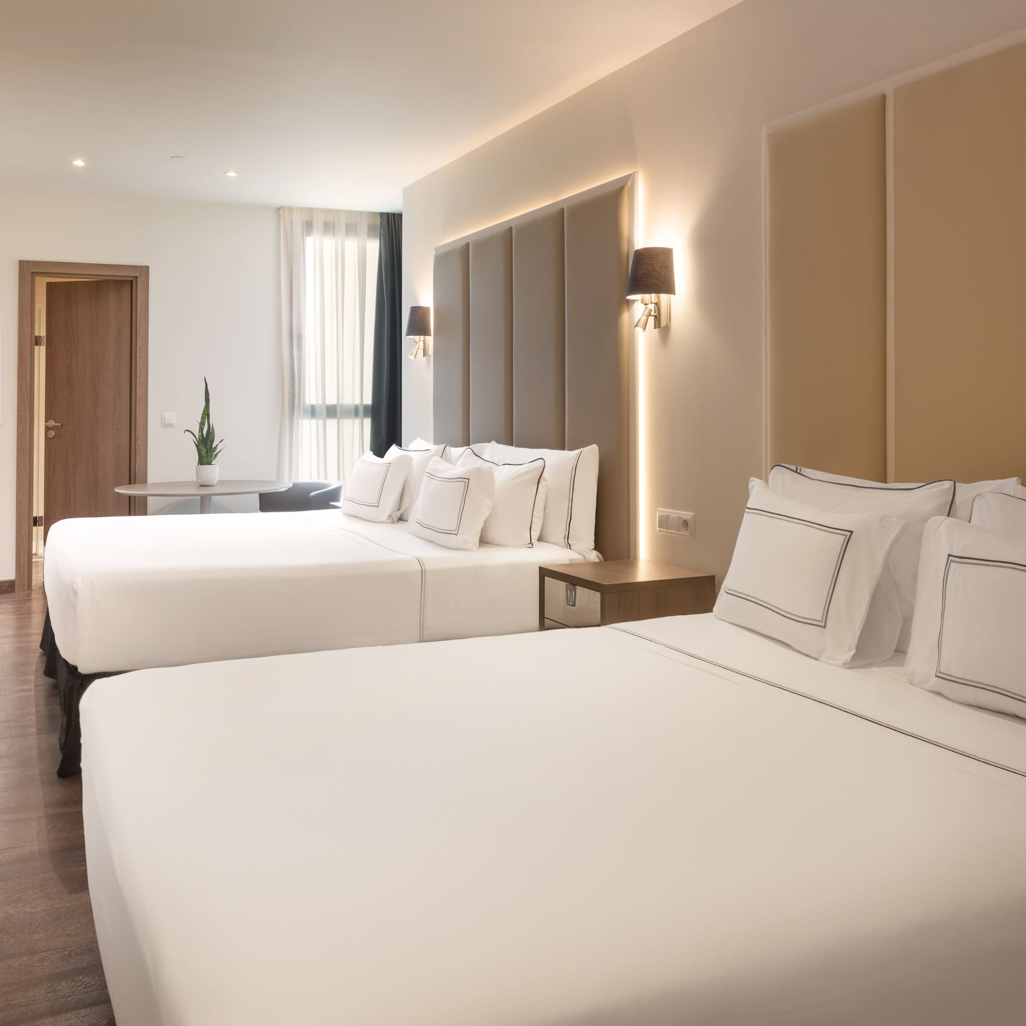 Modern hotel room with two beds, hardwood floor, TV, and ambient lighting.