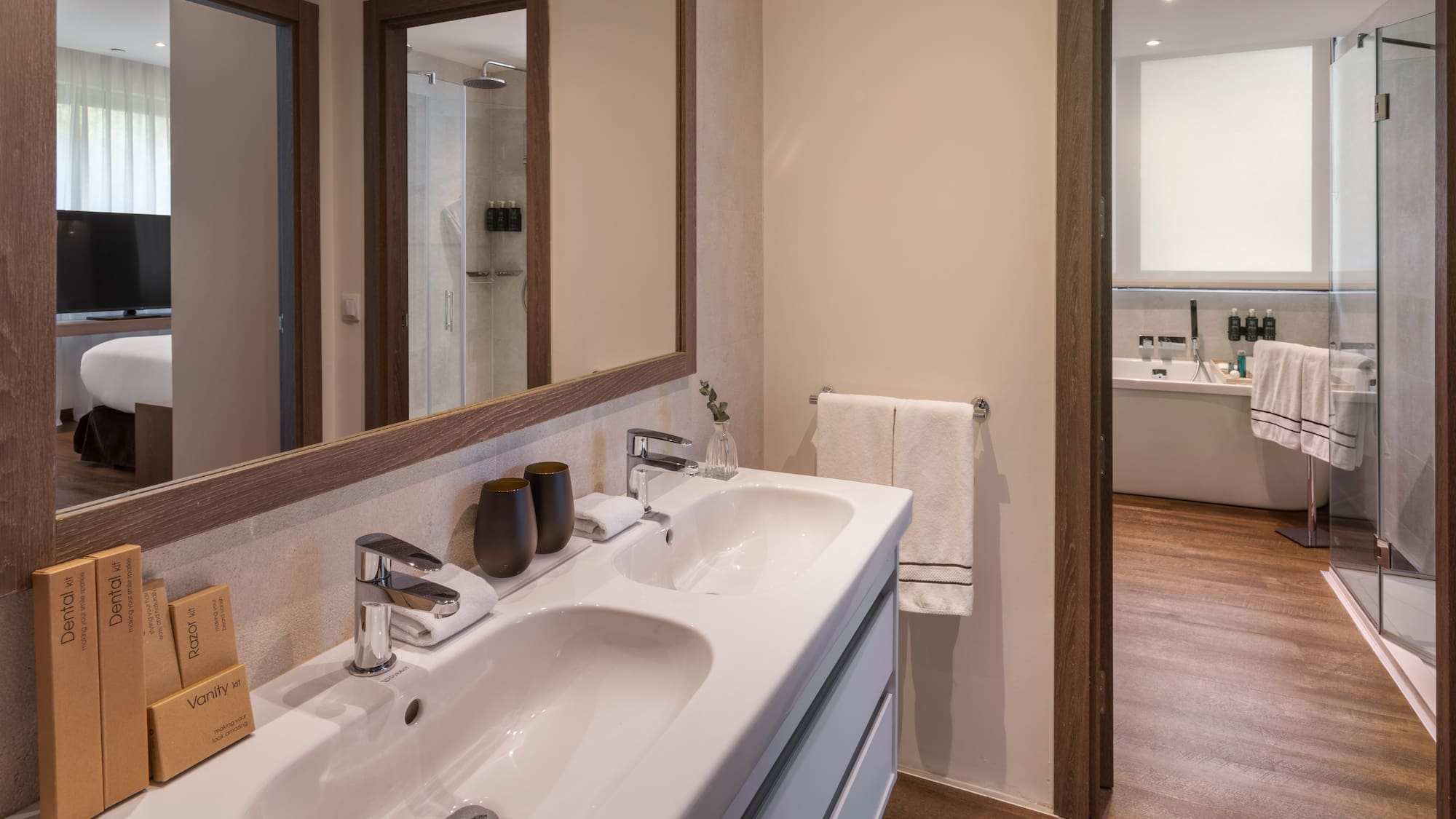 Baño moderno hotel: lavabo doble, espejo, ducha y artículos de tocador.