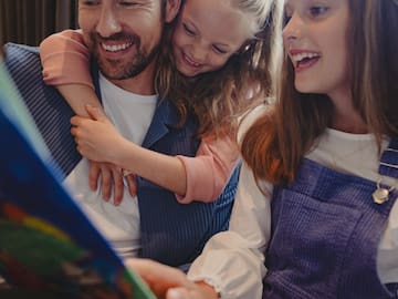 a man and two girls looking at a book