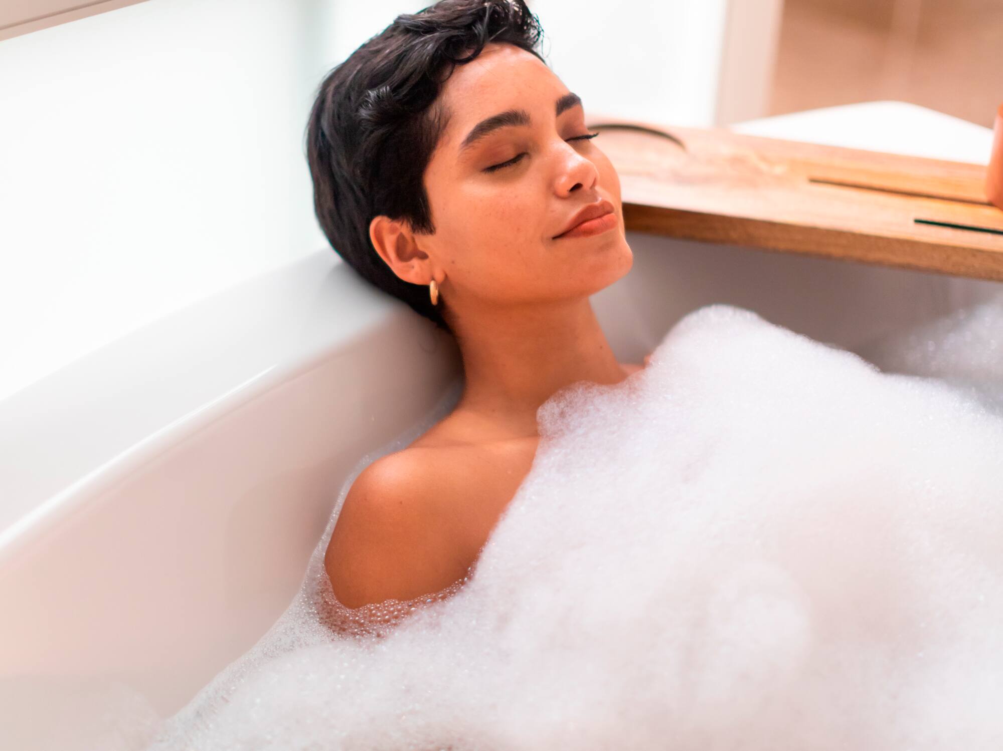 a woman lying in a bathtub with foam