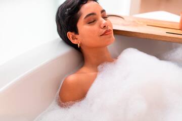 a woman lying in a bathtub with foam