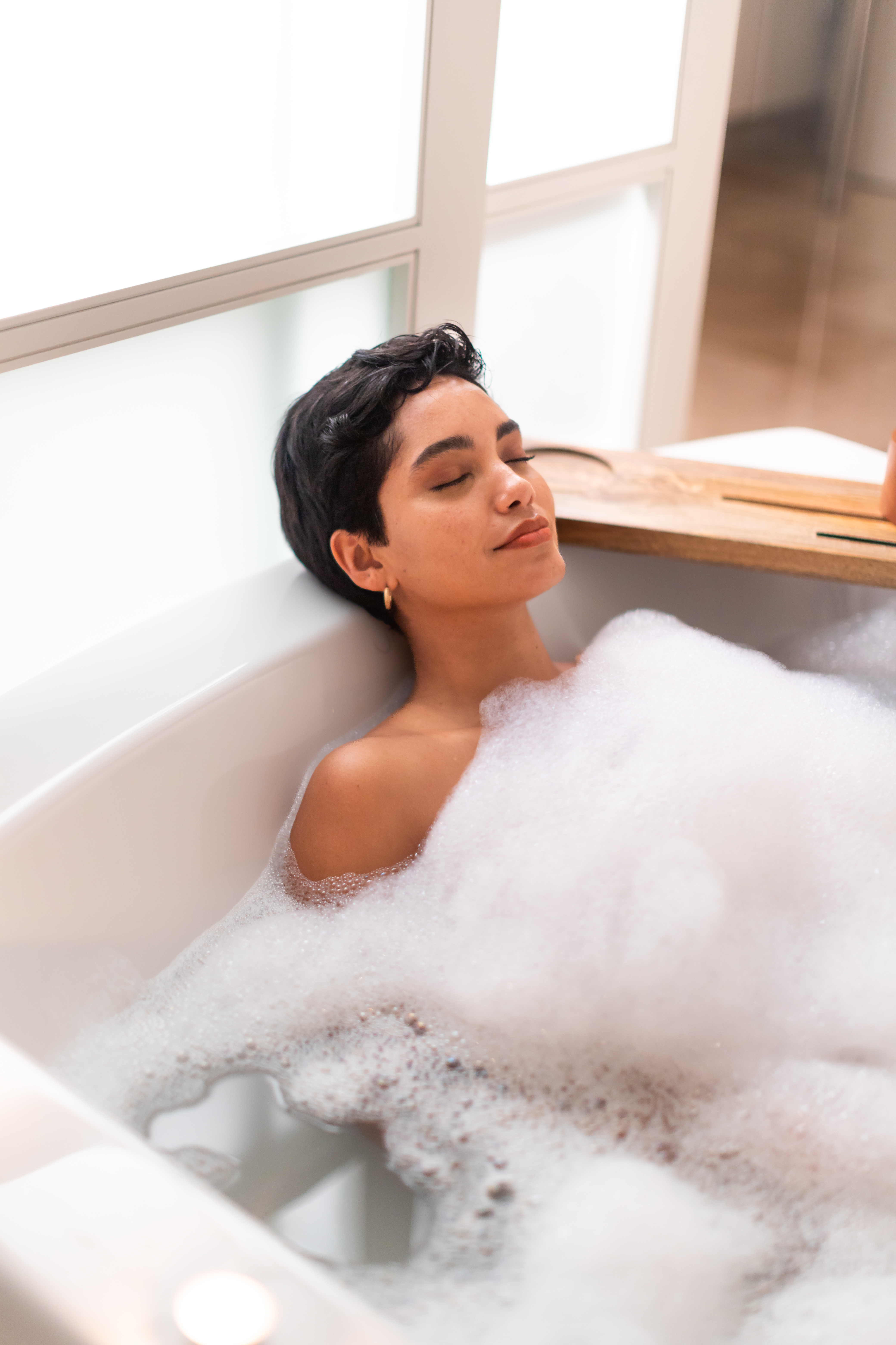 a woman lying in a bathtub with foam