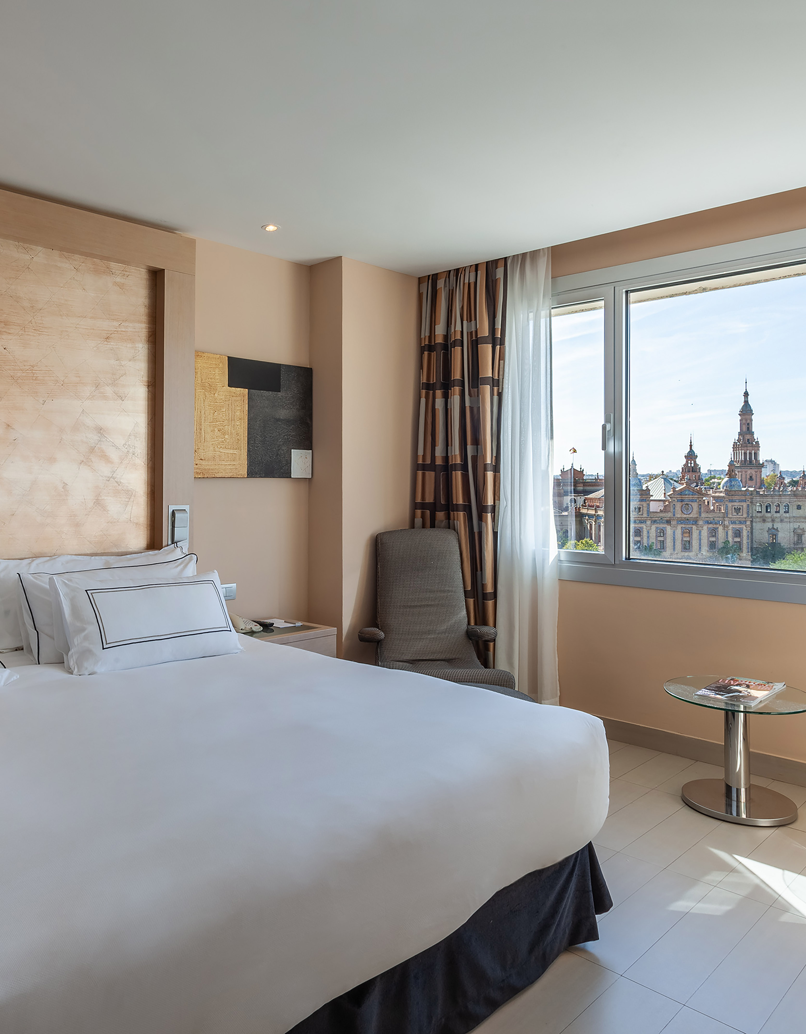 Hotel room with Plaza de España Seville city view from window, comfortable bed.