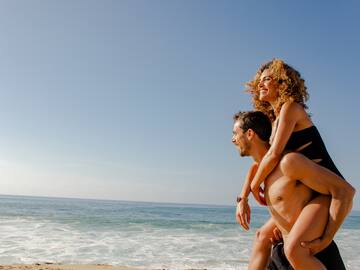 a man carrying a woman on his back on a beach