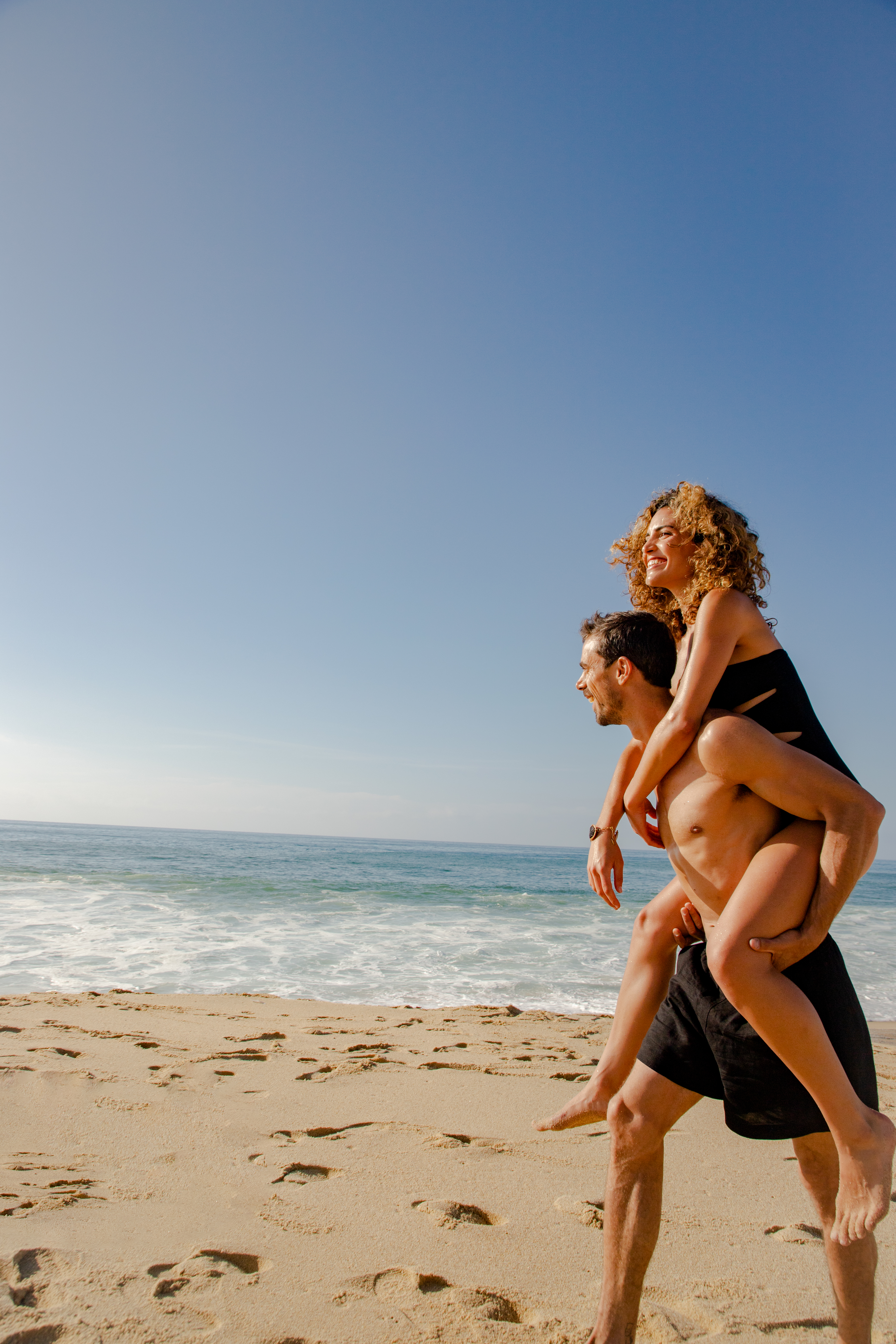 a man carrying a woman on his back on a beach