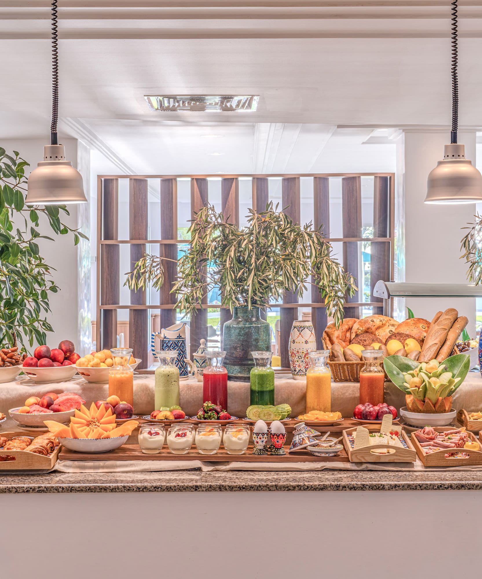 Buffet de desayuno fresco y variado de hotel con frutas, zumos y bollería.