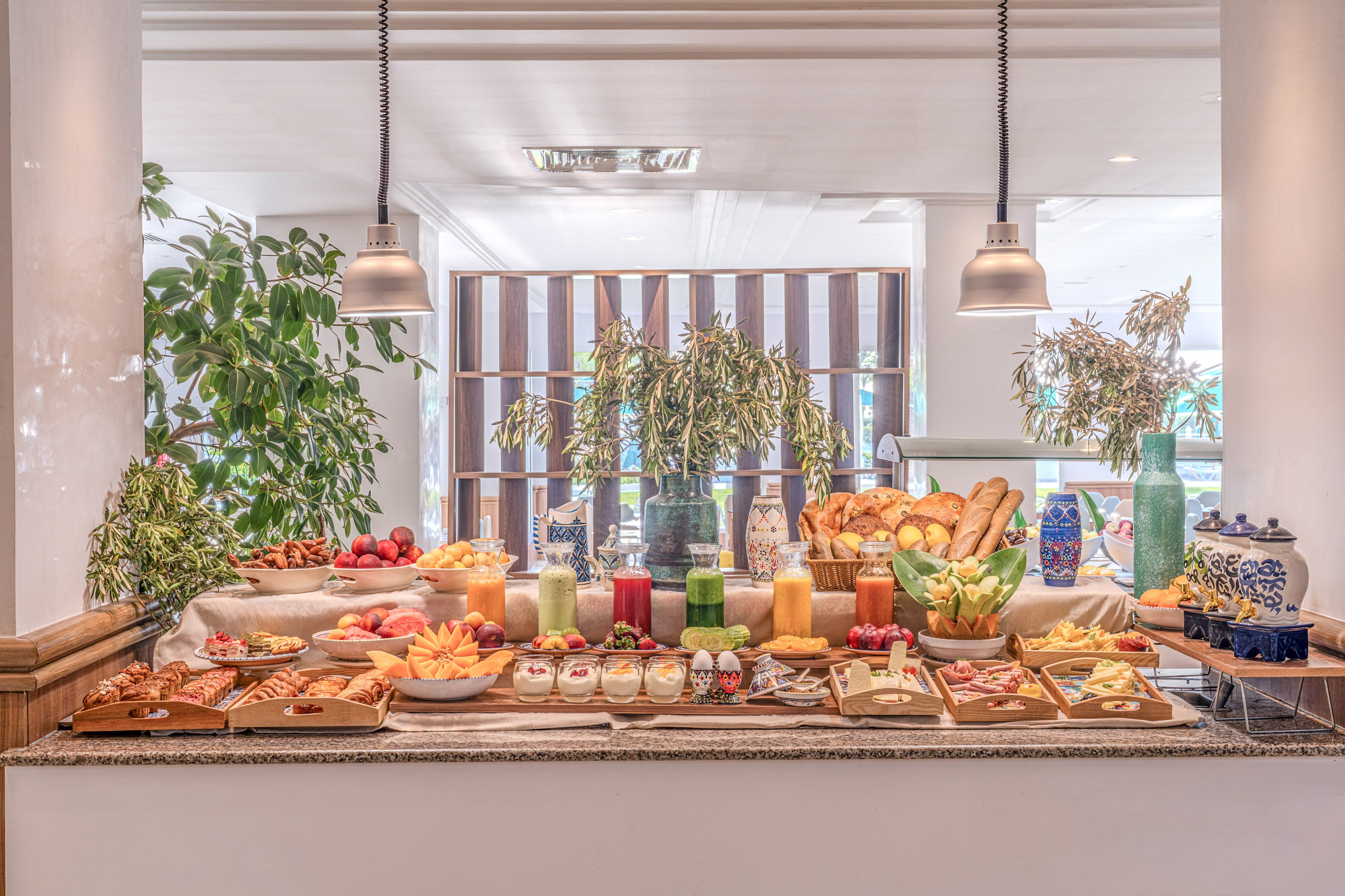 Buffet de desayuno fresco y variado de hotel con frutas, zumos y bollería.