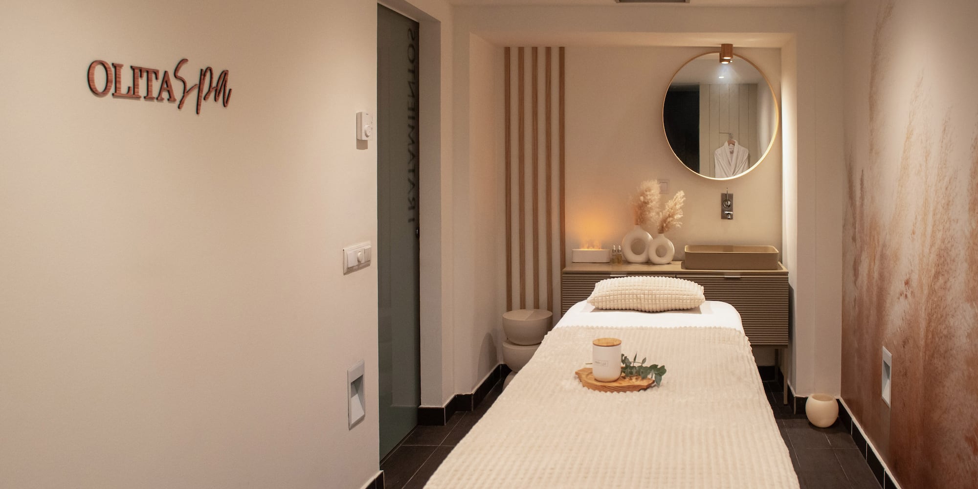 a massage room with a mirror and a bed